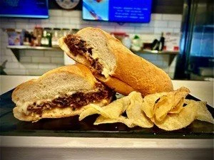 Chocolate chip cookie sandwich with chips on a serving tray in a restaurant or cafe setting.