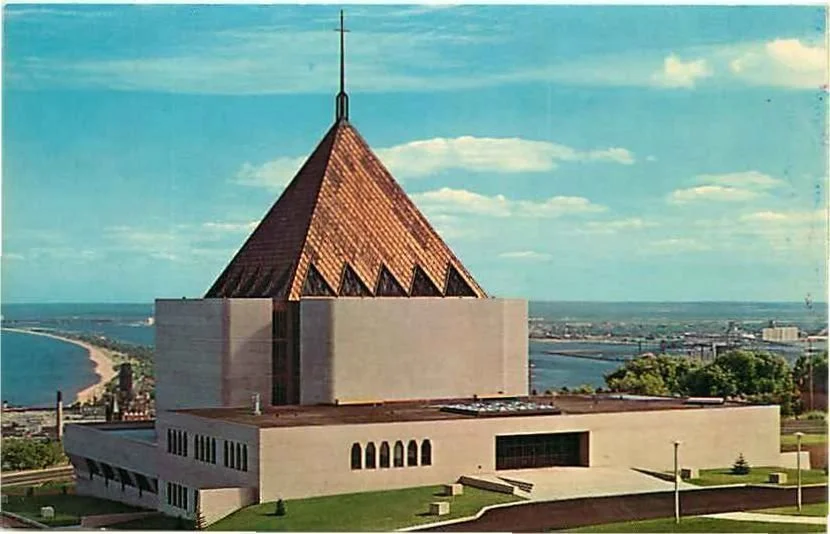 First United Methodist Church with it's distinctive triangular, copper roof and a cross on top, overlooking Lake Superior and a Duluth's skyline.