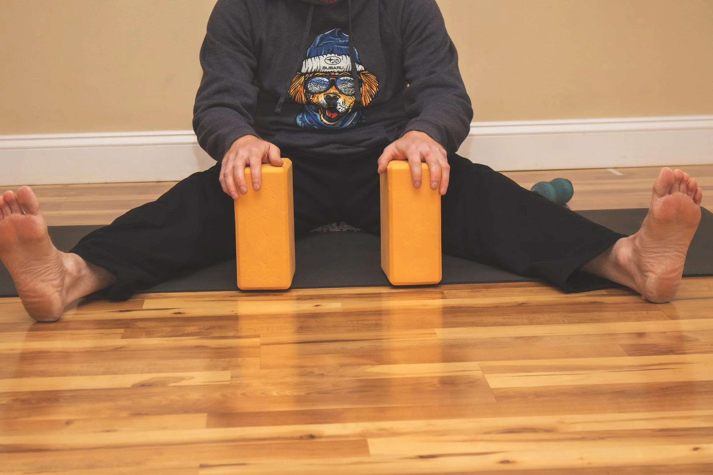 Matthew Healey demonstrating a wide-legged forward fold using blocks at Joy of Yoga.