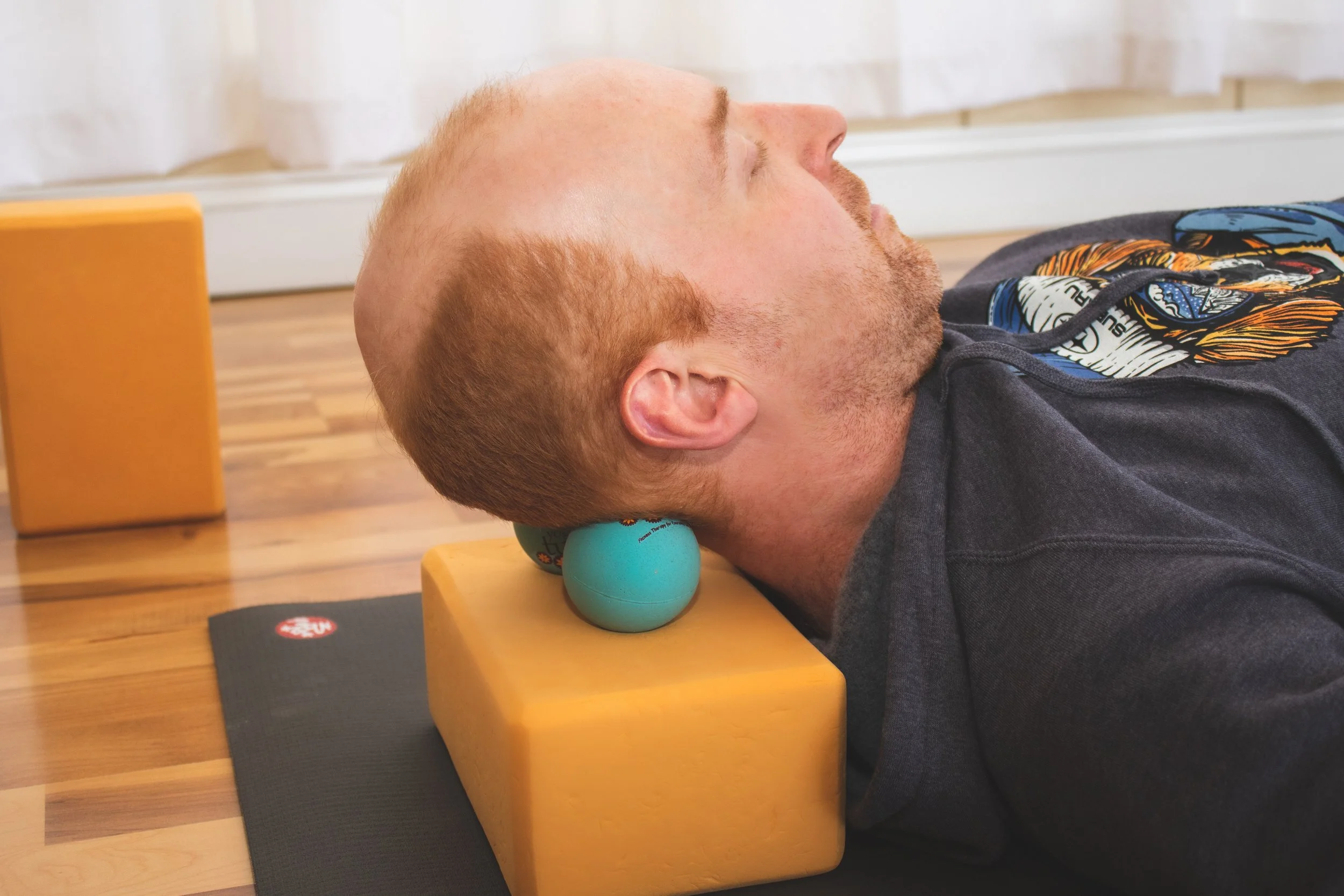 Matthew Healey  at Joy of Yoga showing how massage therapy balls can be used on the occipital bones to promote greater relaxation.