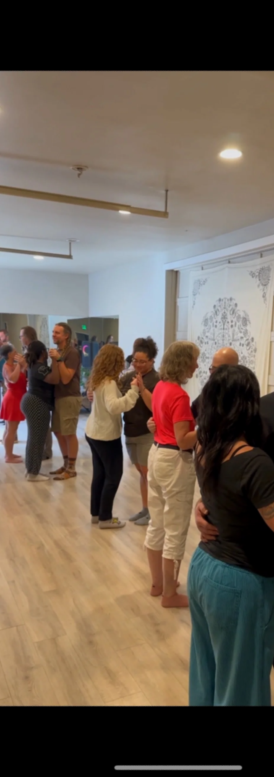 People dancing in pairs at an indoor social gathering, group dance class, or dance event.