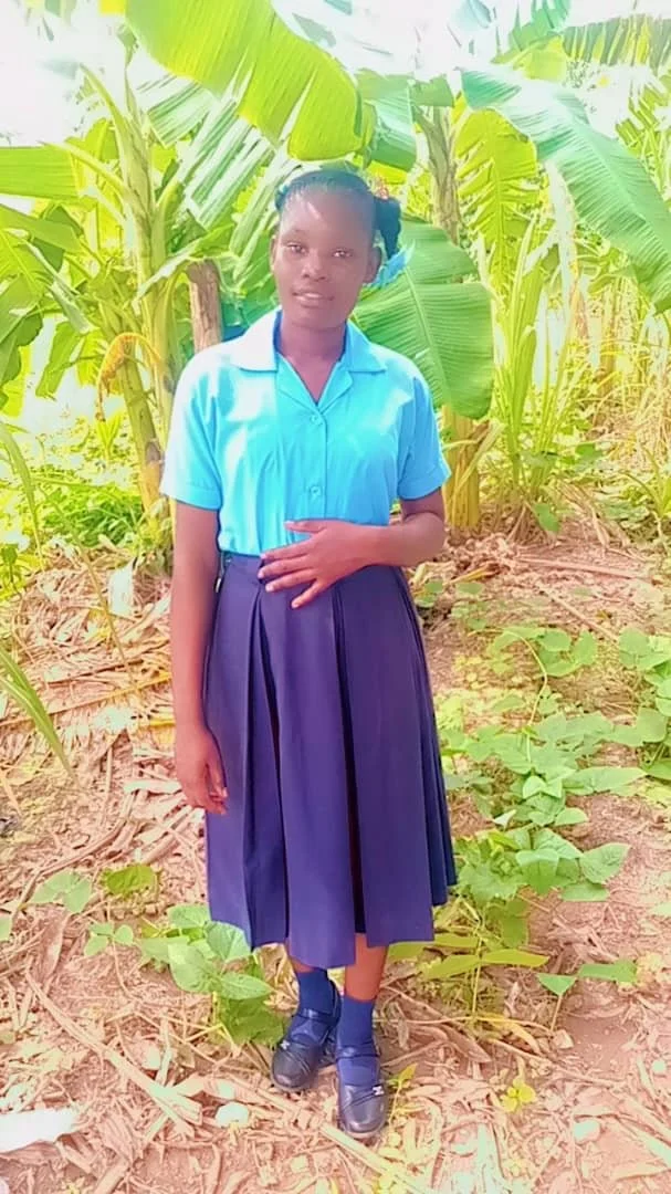 A student in school uniform standing outdoors in Haiti.