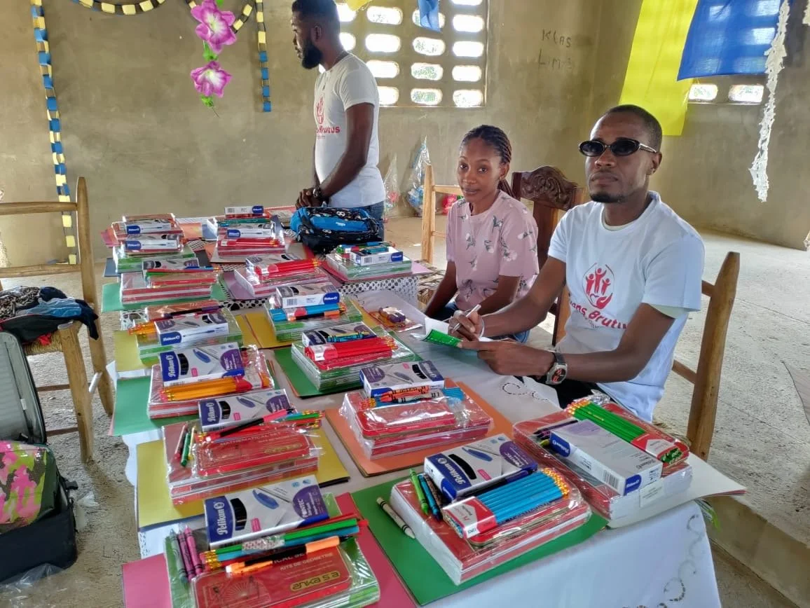 Evens Brutus Foundation team members with notebooks, pencils, and school supplies arranged for distribution.