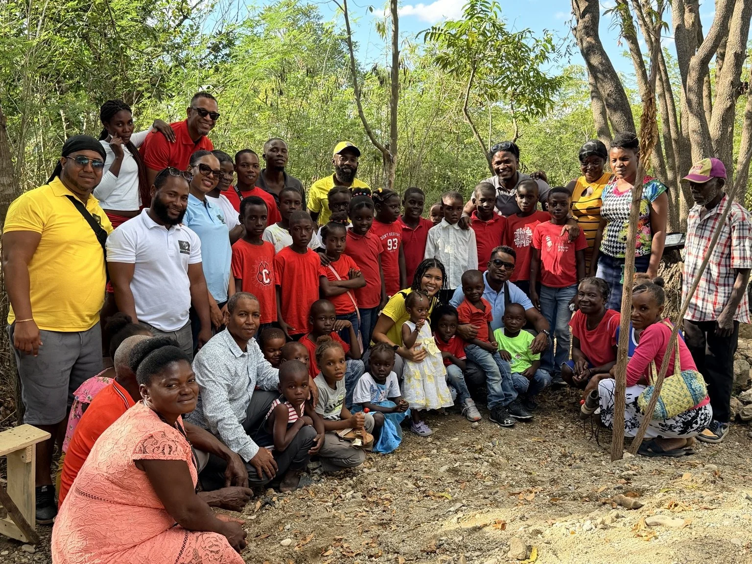Children, families, and Evens Brutus Foundation volunteers gathered outdoors during a community visit.