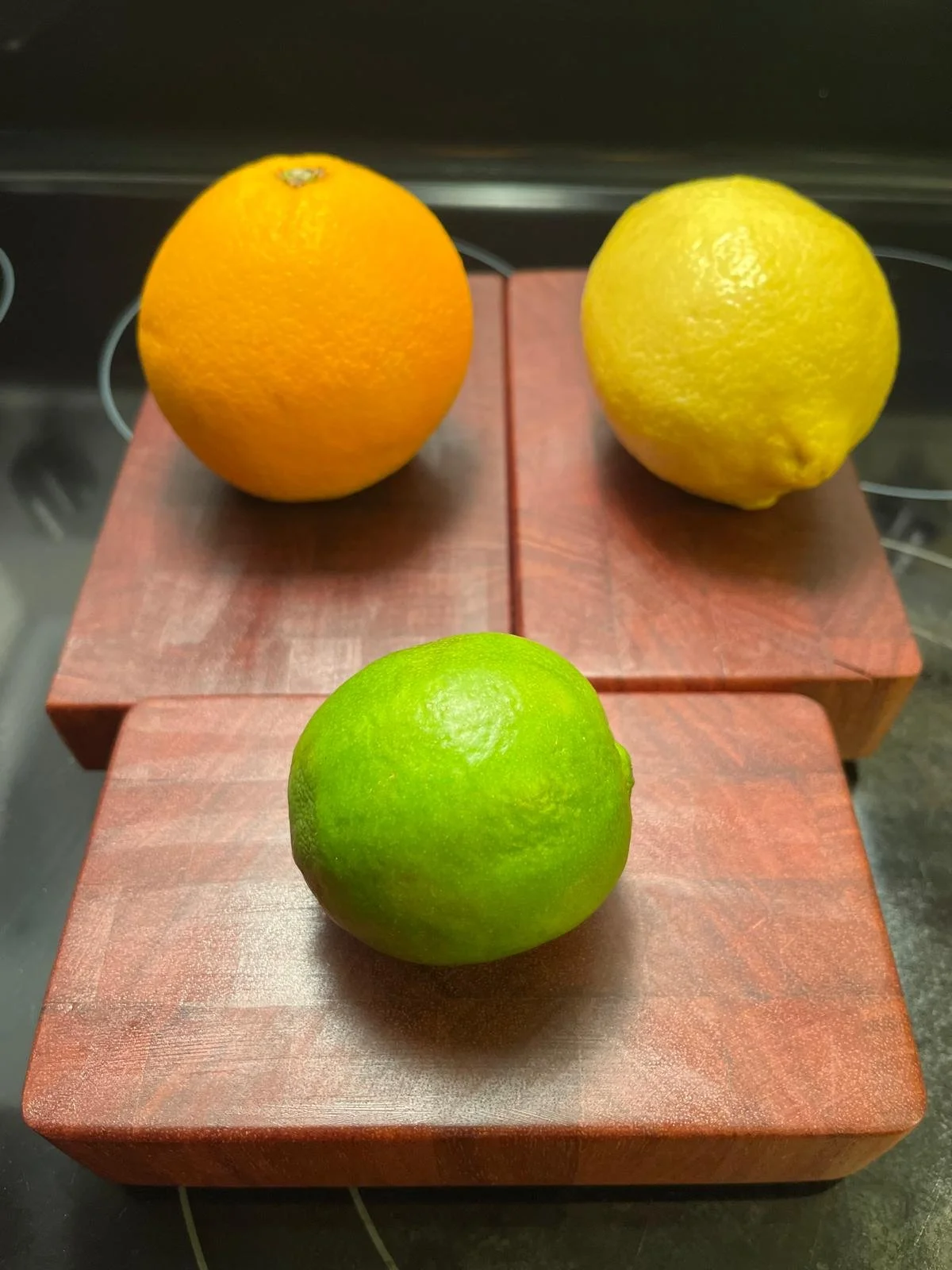 Orange, lemon, and lime fruits on mahogany cutting boards.