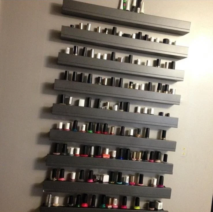 Wall-mounted shelves holding various bottles of nail polish.