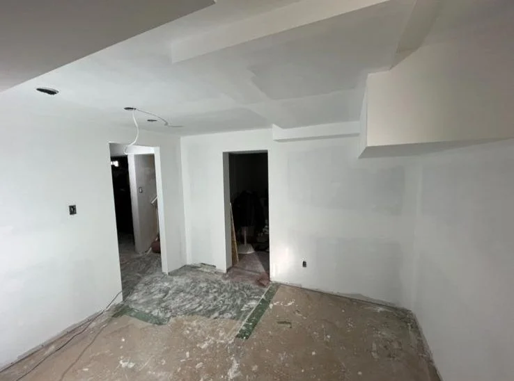 Room under construction with white painted walls, unfinished flooring, and open doorways to other rooms.