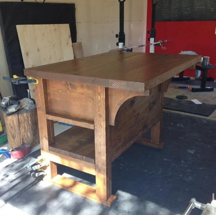 Wooden workbench in a workshop with clamps and tools.