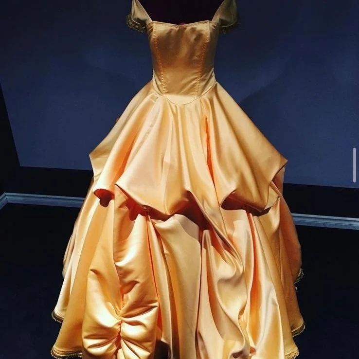 Elegant gold-colored ball gown with a fitted bodice and a full, ruffled skirt on display.