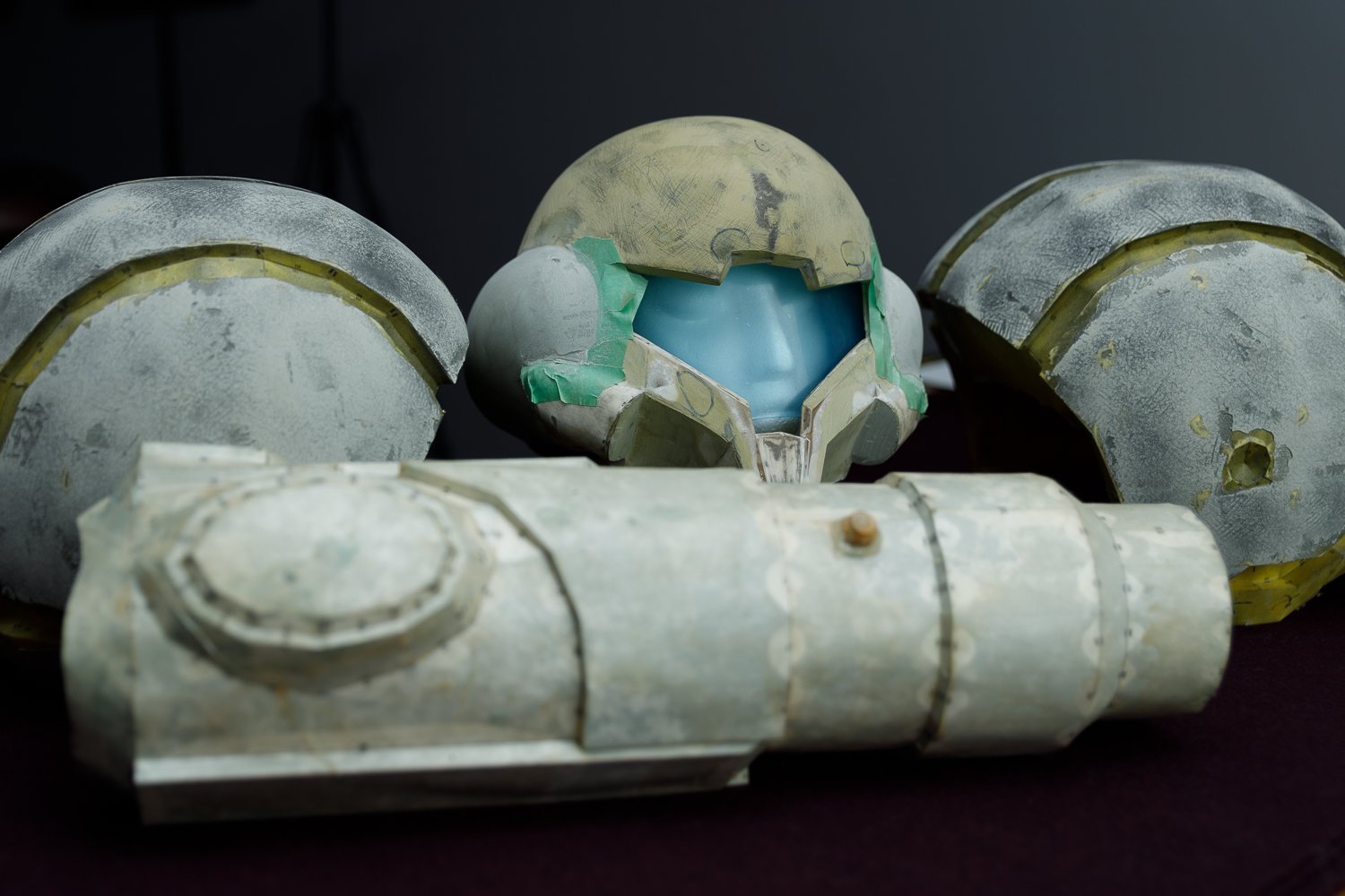 A detailed replica or prop of a futuristic helmet and armor, resembling a space or science fiction theme, with a blue visor and worn, weathered paint.