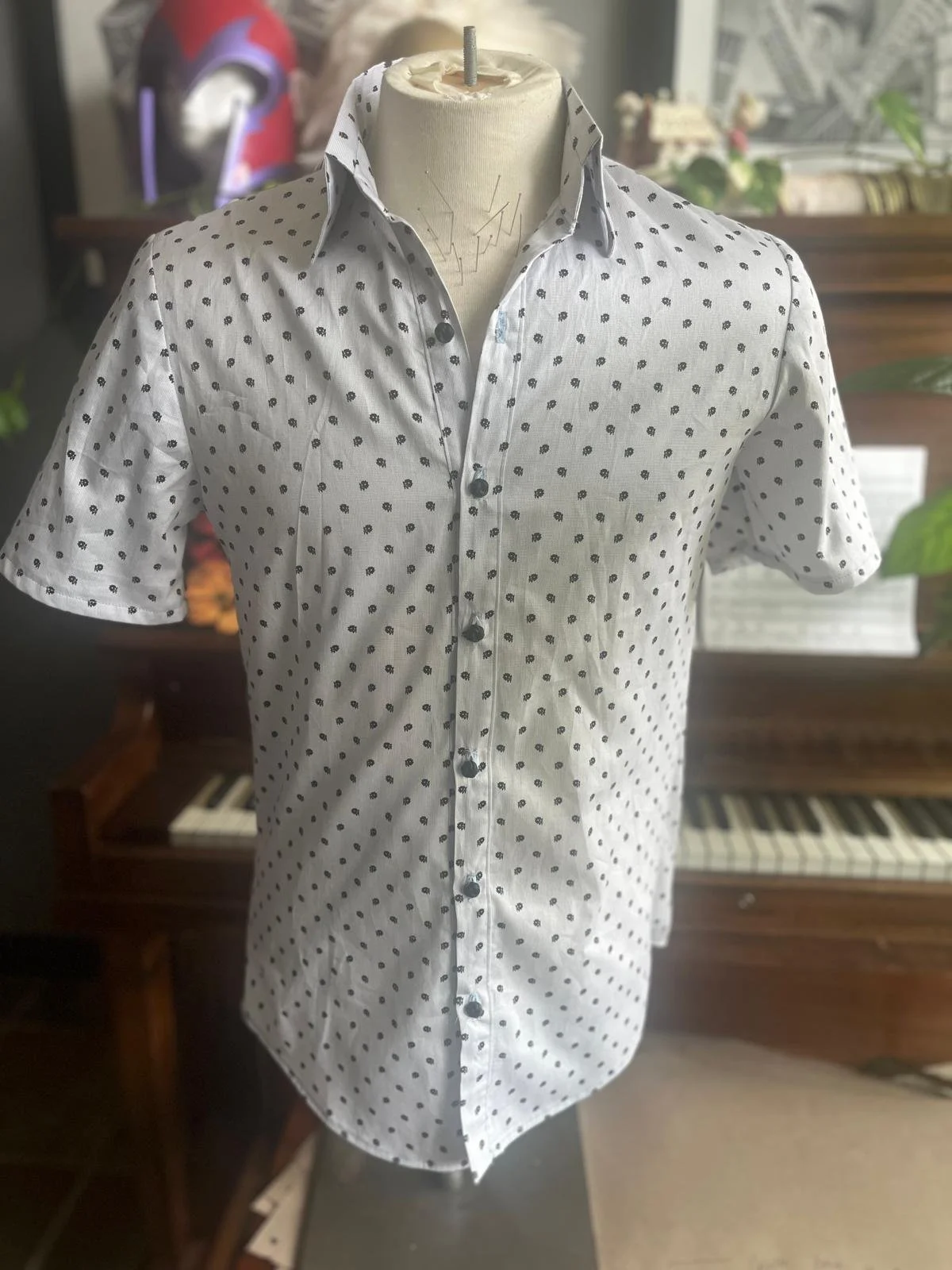 White short-sleeve button-up shirt with small flowers on a mannequin torso.