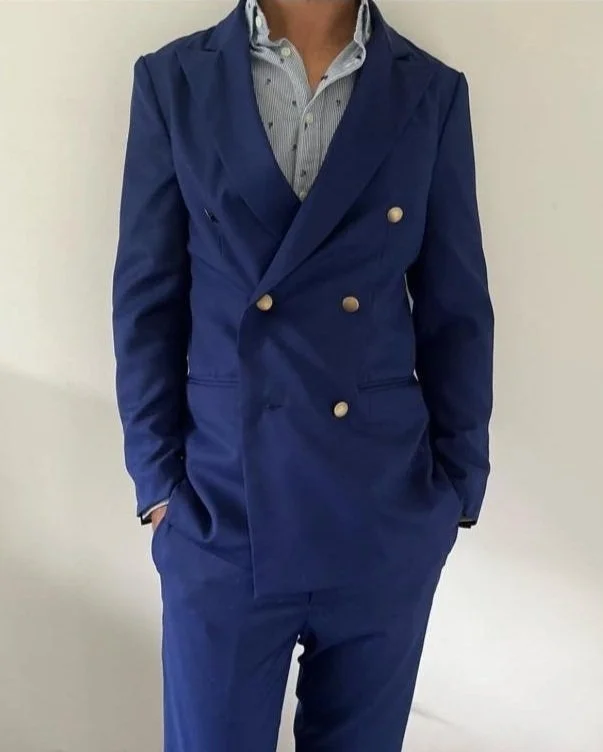 Person wearing a blue double-breasted suit jacket with gold buttons and matching blue pants, paired with a light blue, striped button-up shirt.