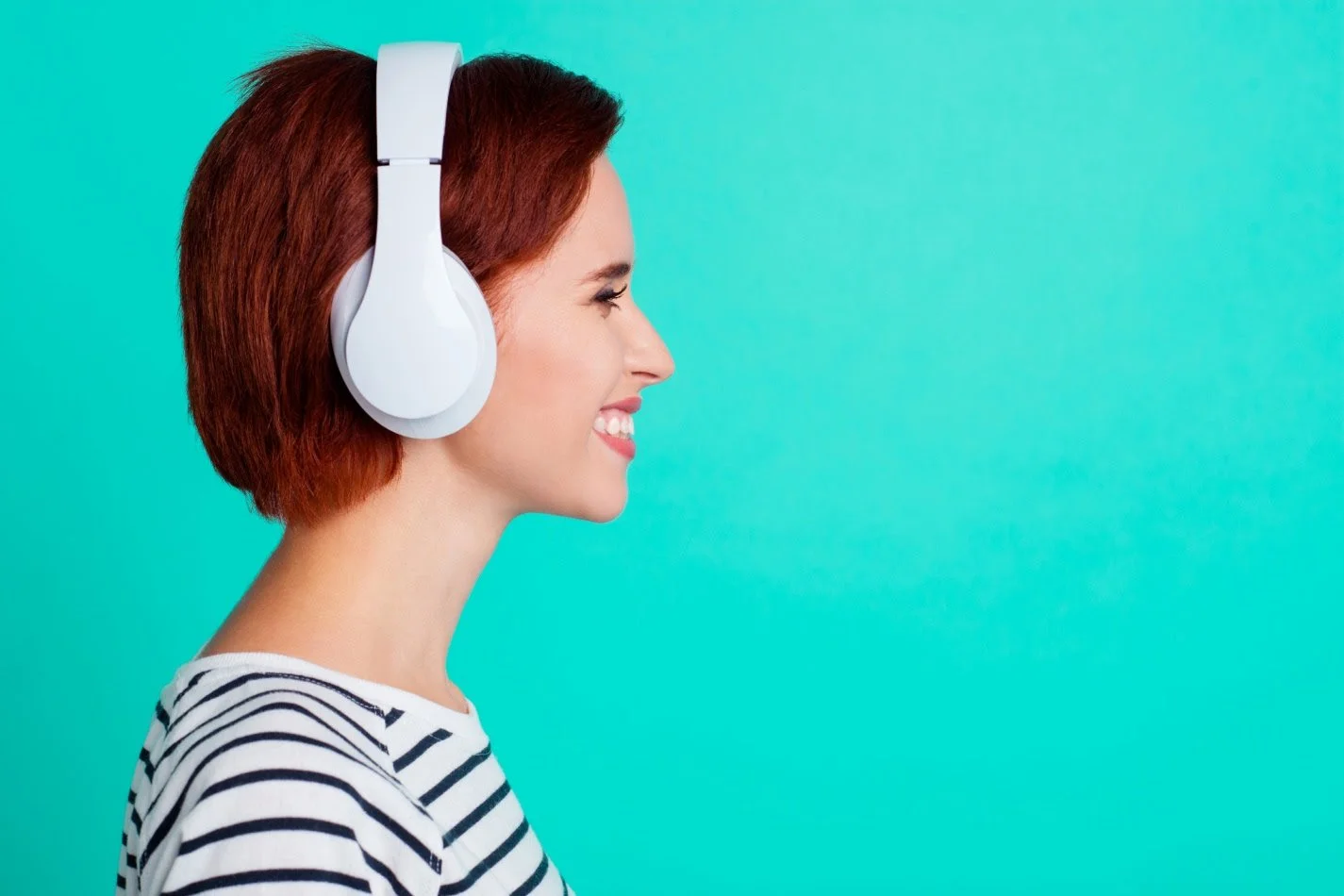 Smiling woman in profile wearing white headphones