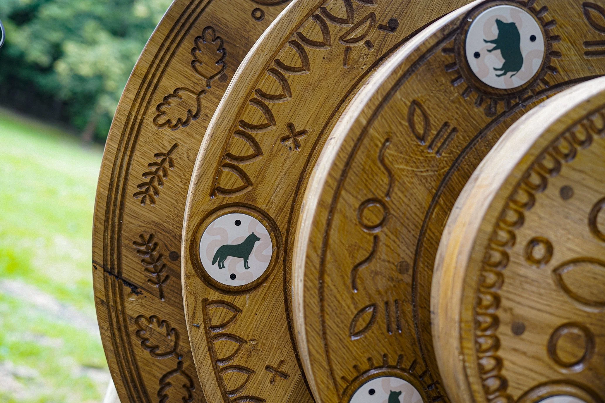 Close-up of a wooden clock with carved details and a circular emblem featuring a bear silhouette.