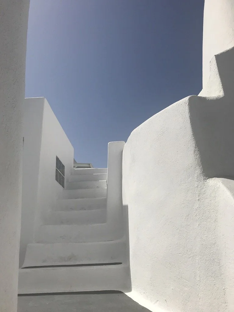 White staircase between white walls under a clear blue sky.