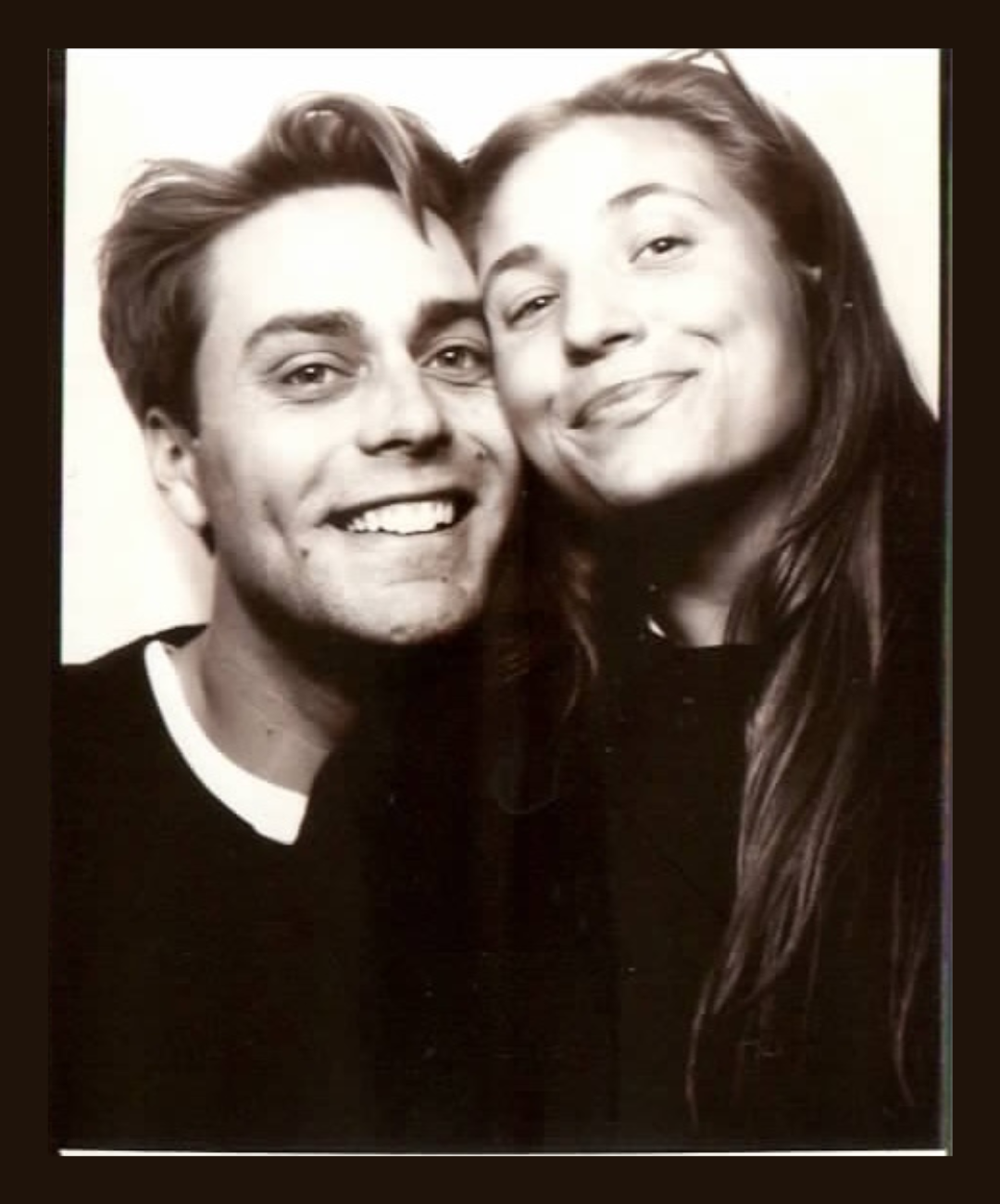 Black and white photo of a smiling young man and woman close together, both facing the camera.
