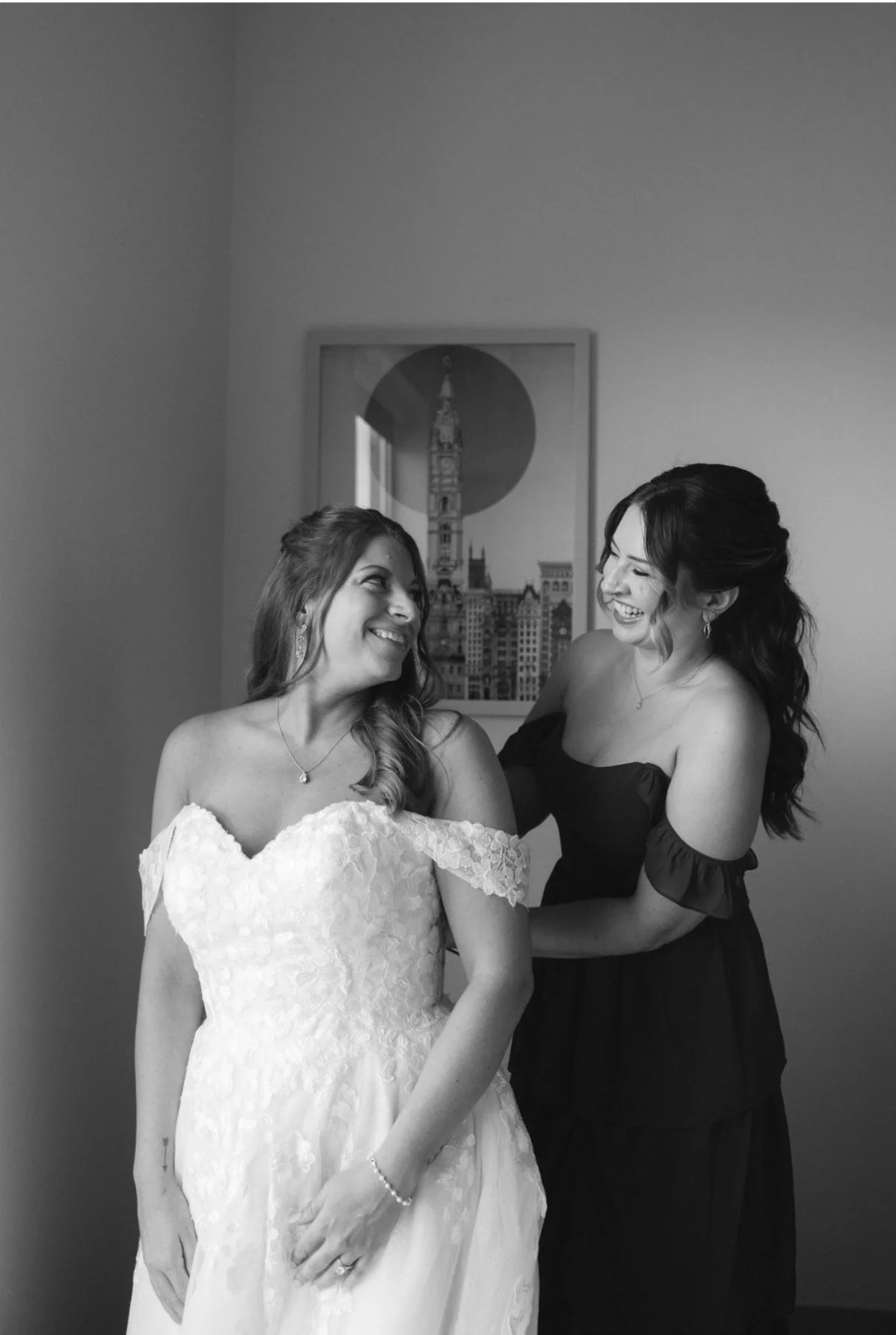 Black and white photo of a woman with short curly hair sitting outdoors at night, looking to the side with a slight smile, wearing a collared jacket.