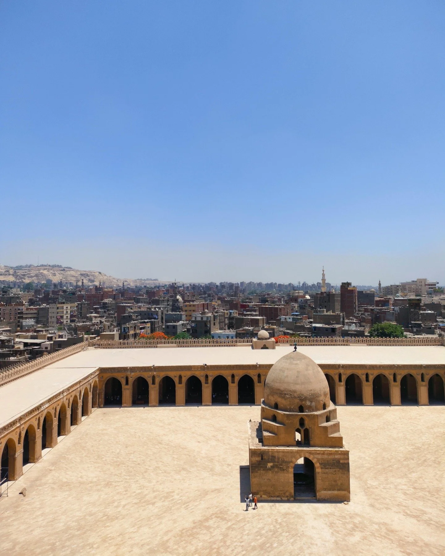 The courtyard at Ibn Tulun Mosque measures 92 &times; 92 meters, making it one of the largest uninterrupted worship spaces ever built. Five arcades line the qibla side, every arch pointed, every surface carved stucco. The fountain in the center came 