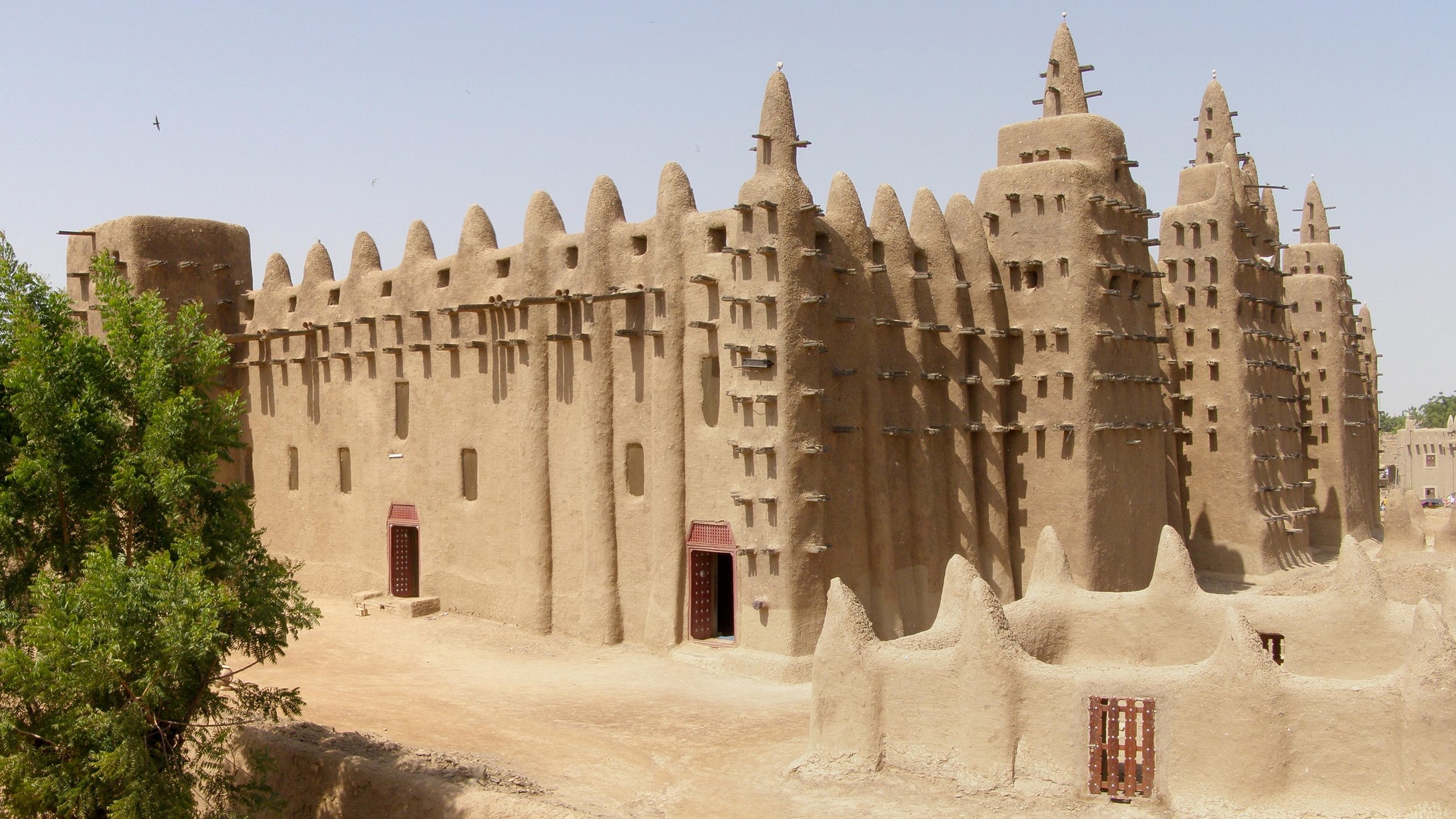 The Great Mosque of Djenn&eacute; is the largest mud-brick building in the world.

Every surface is banco: clay, water, shea butter, baobab powder, and rice husks. The three minarets rise nearly 20 meters from a raised platform above the Bani River f