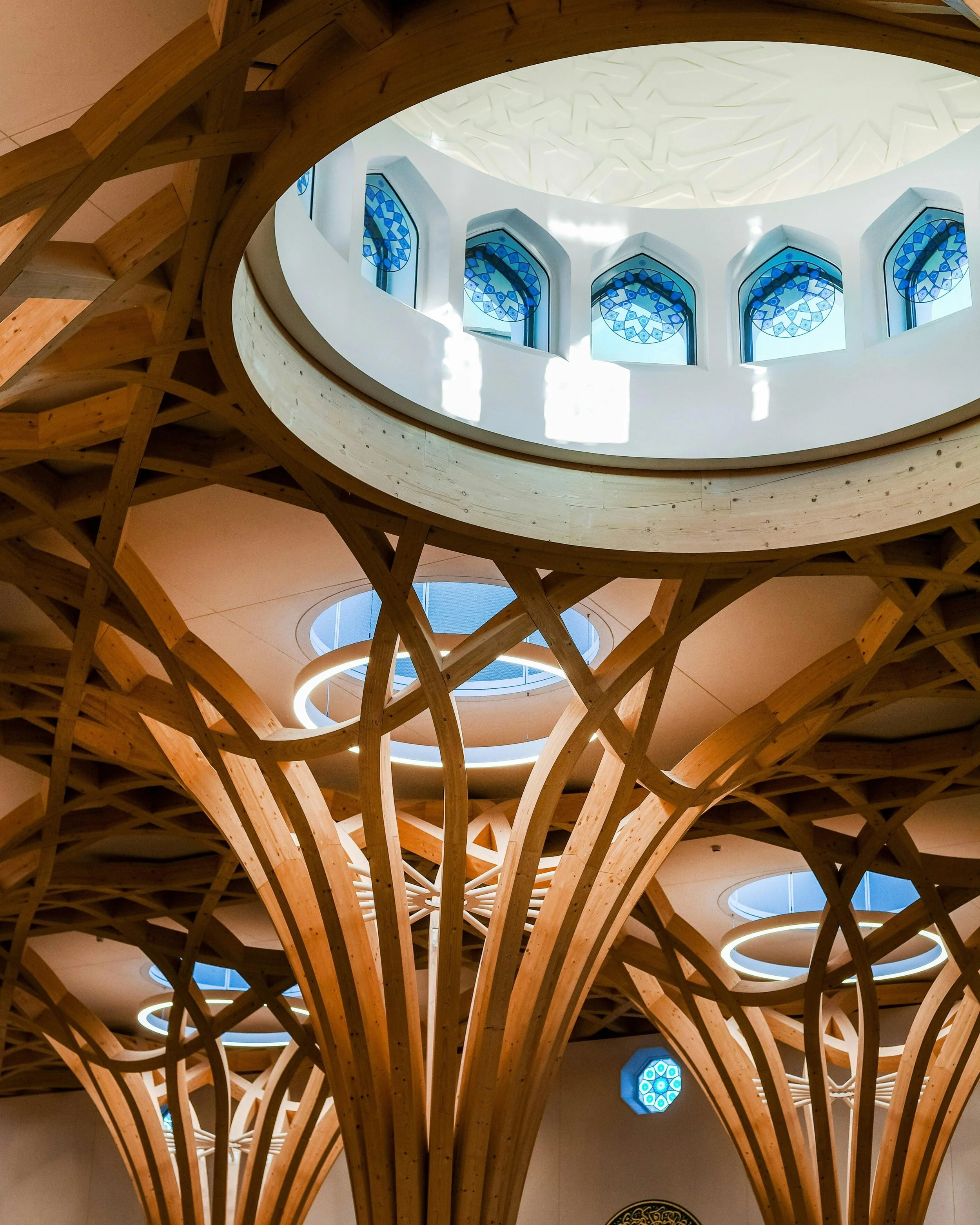 The brick facade of @cambridgecentralmosque spells out a Quranic verse in Kufic calligraphy. You can only read it at close range. From the street, it reads as ordinary Cambridgeshire brickwork.

Inside the prayer hall, glulam timber columns branch up