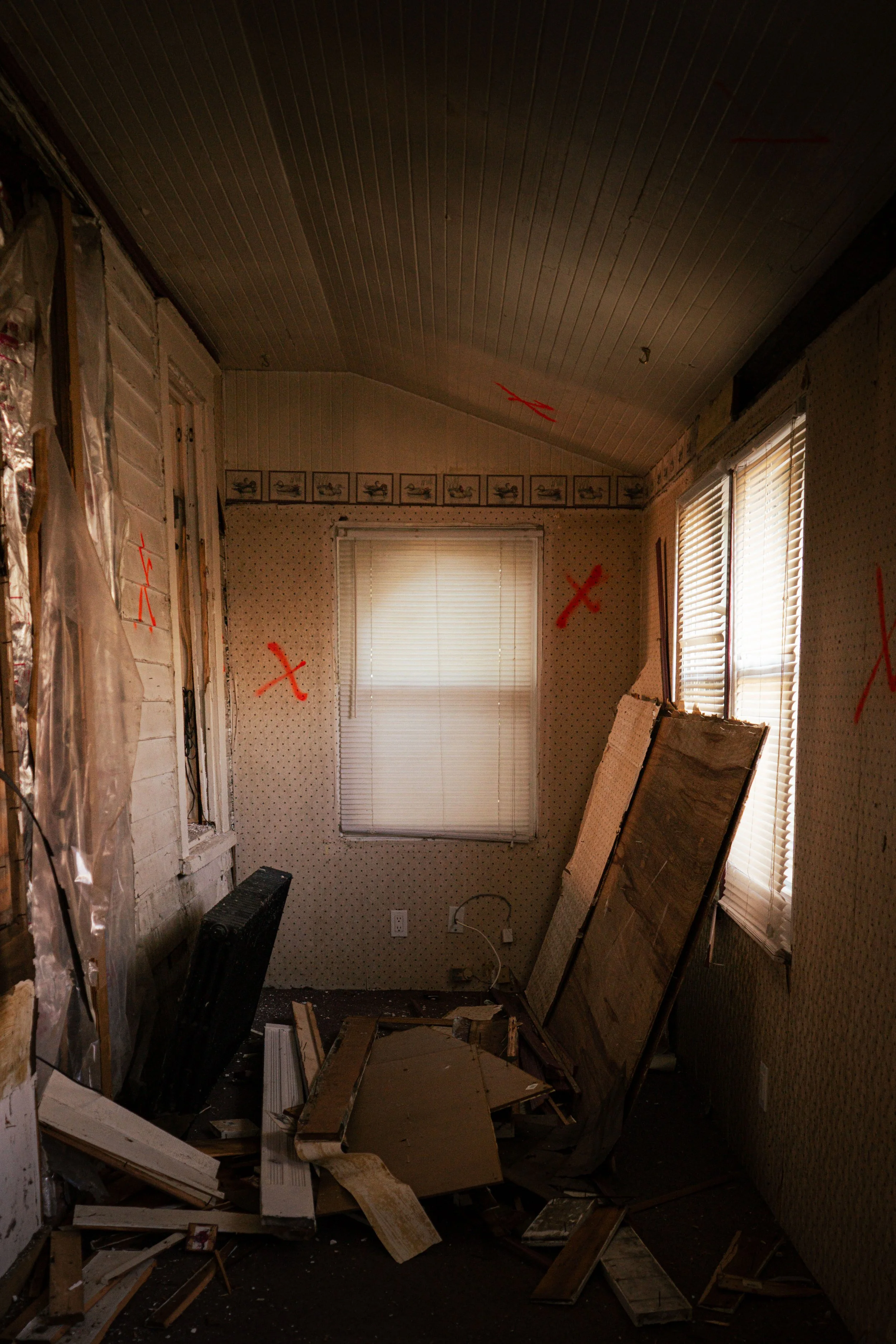 Interior of small room under renovation with debris and red X markings — architectural fine-art photo by DRiccardi Photography.