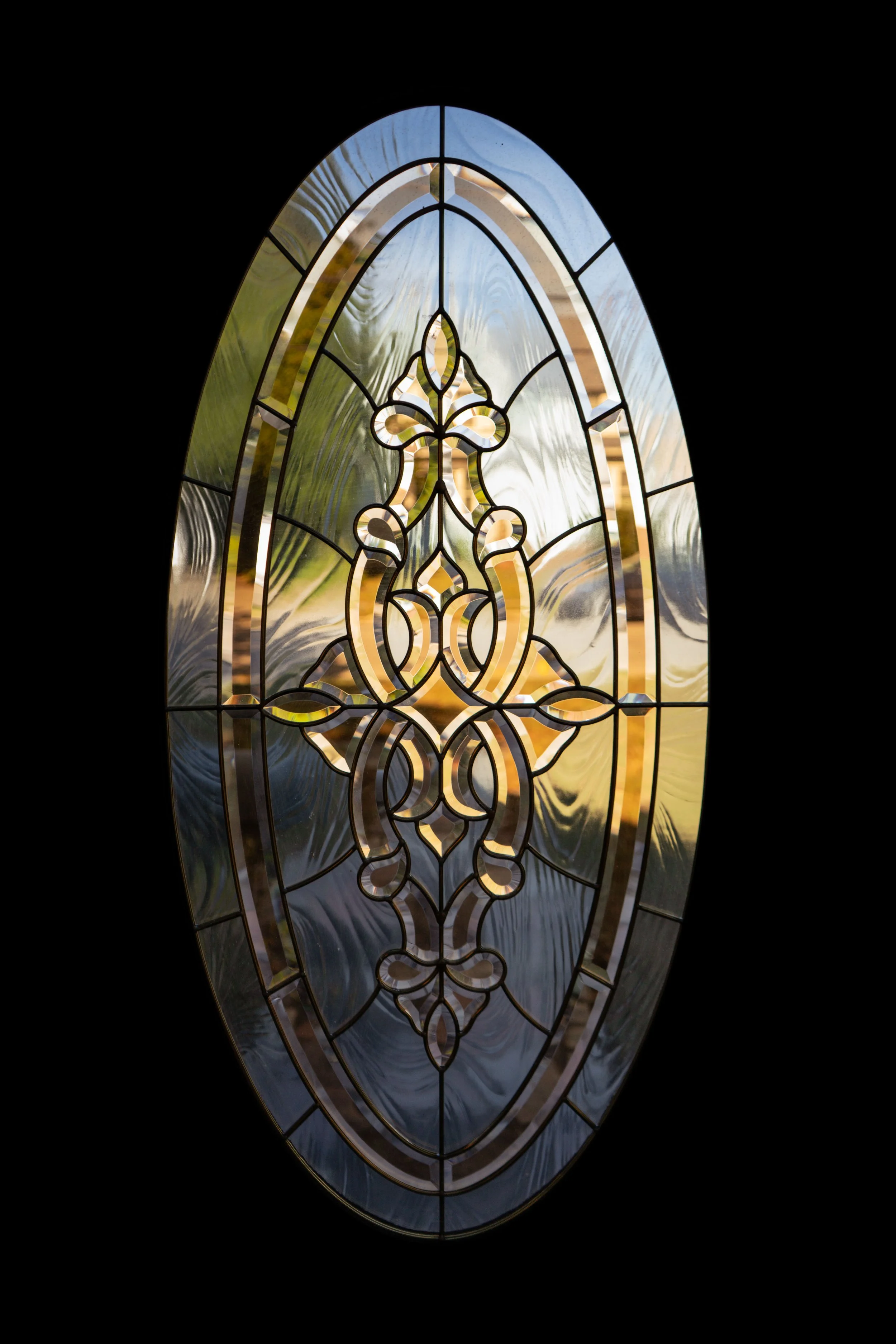 Close-up of oval stained-glass window with decorative gold and clear glass pattern — artistic detail photo by DRiccardi Photography.