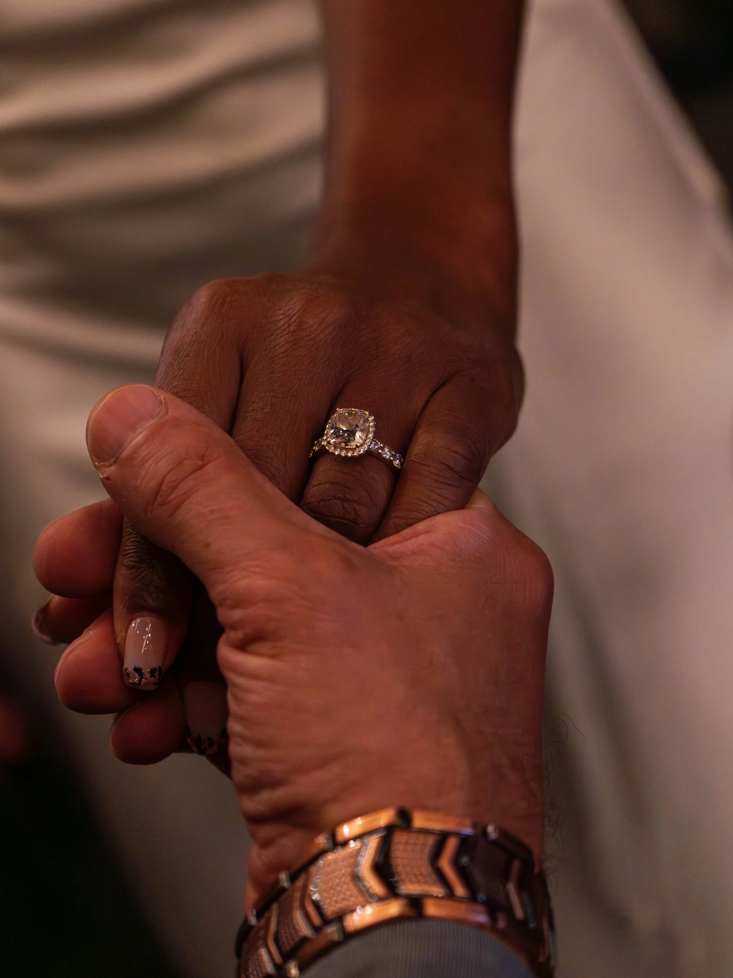 Close-up of couple holding hands showing diamond engagement ring — romantic detail photography by DRiccardi Photography, New York.