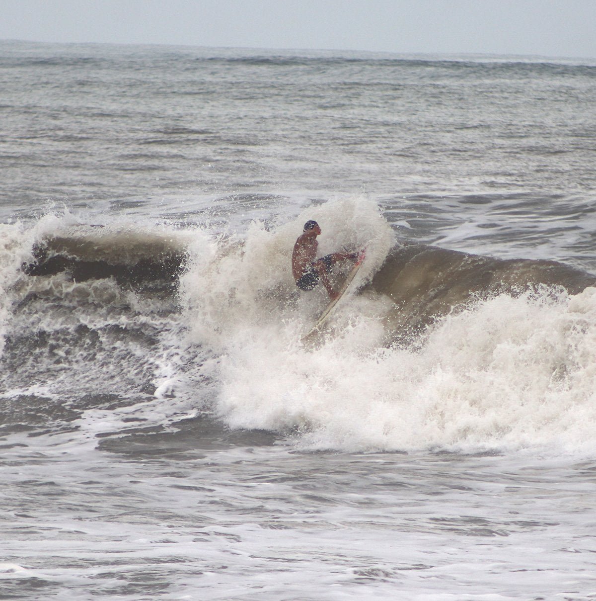 surfing the break at Guanico Beach Resort with a demo surfboard