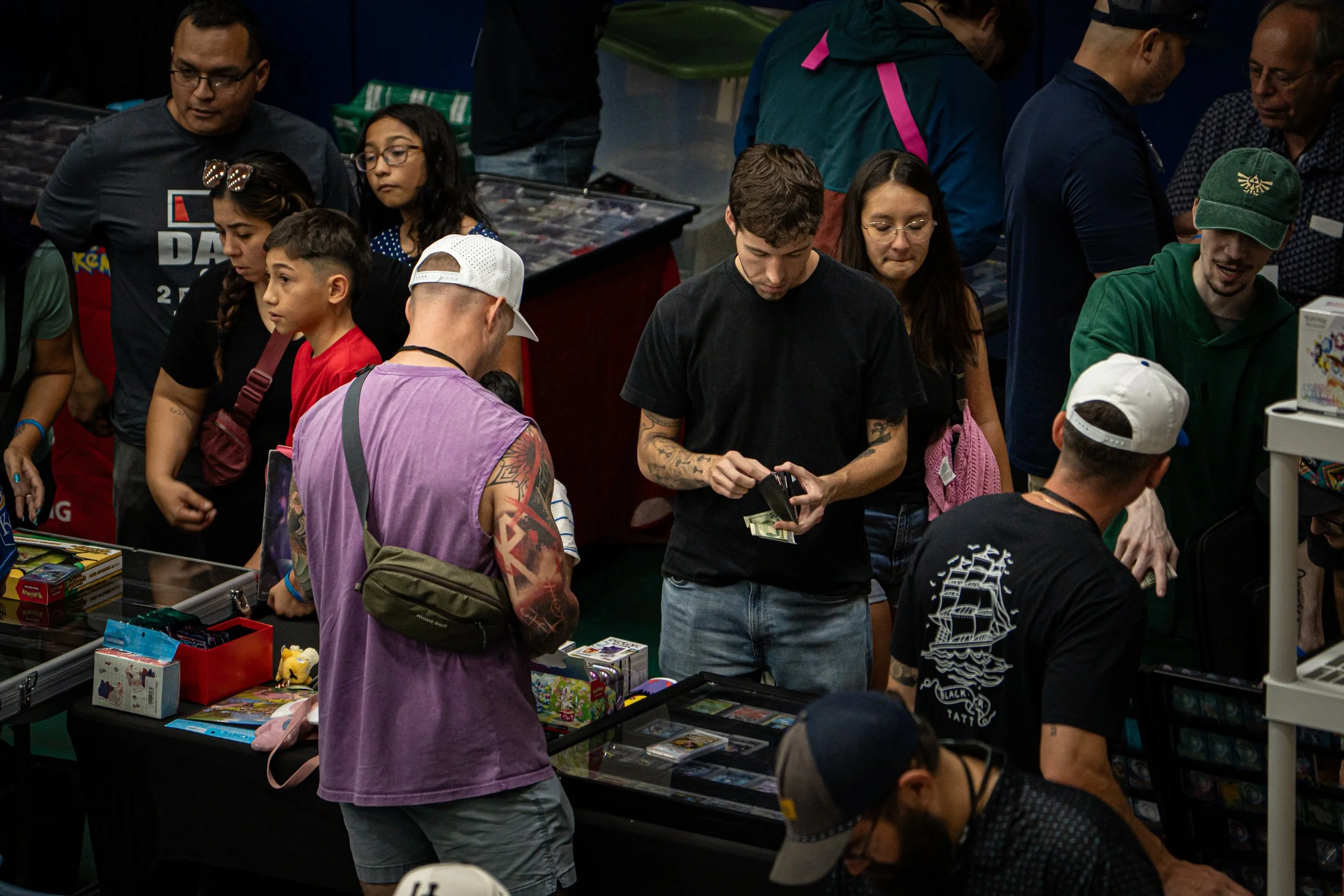 People at a booth shopping for toys and games at a convention or event.