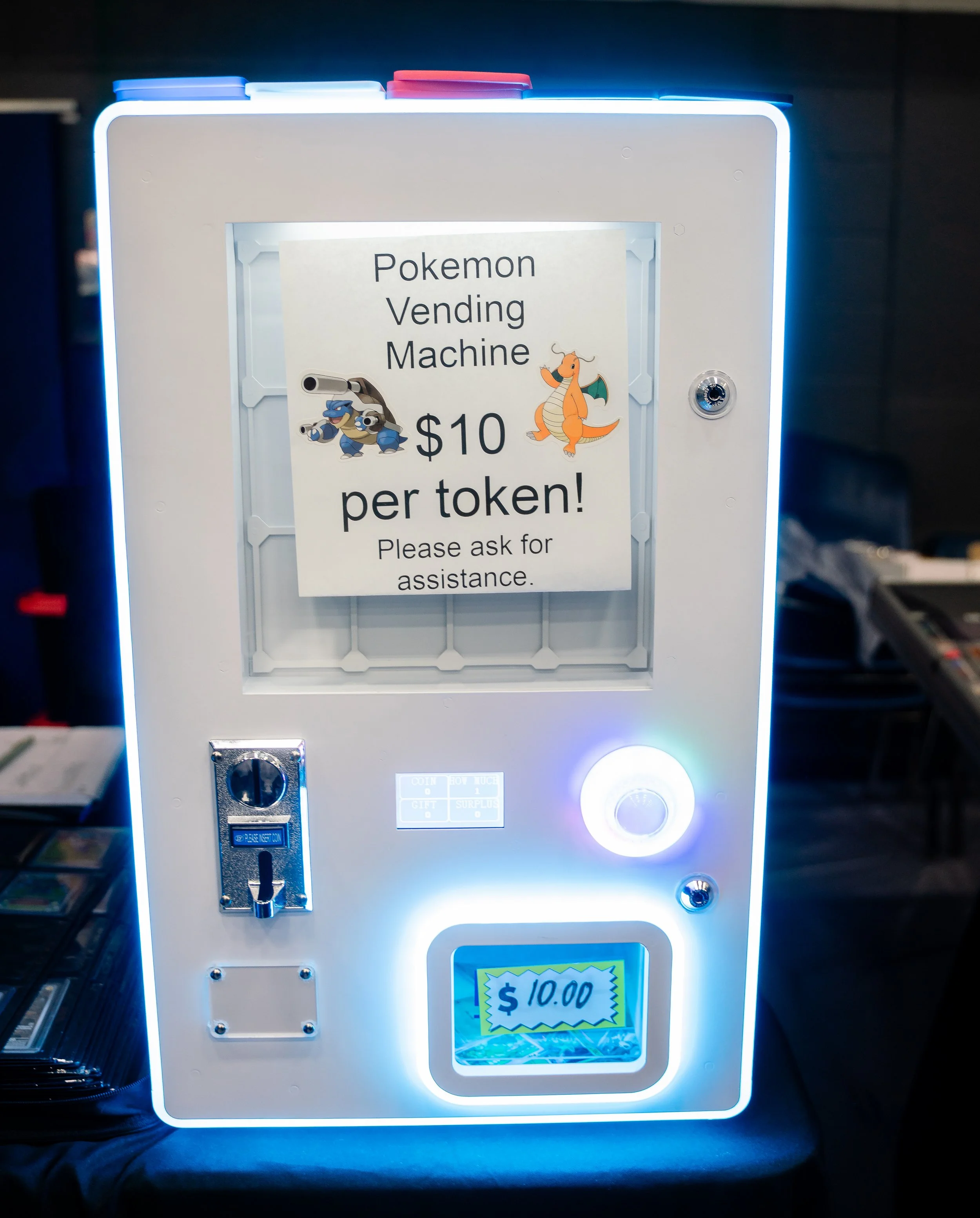 A vending machine with a sign that reads 'Pokemon Vending Machine $10 per token! Please ask for assistance.' The machine displays a price of $10.00.