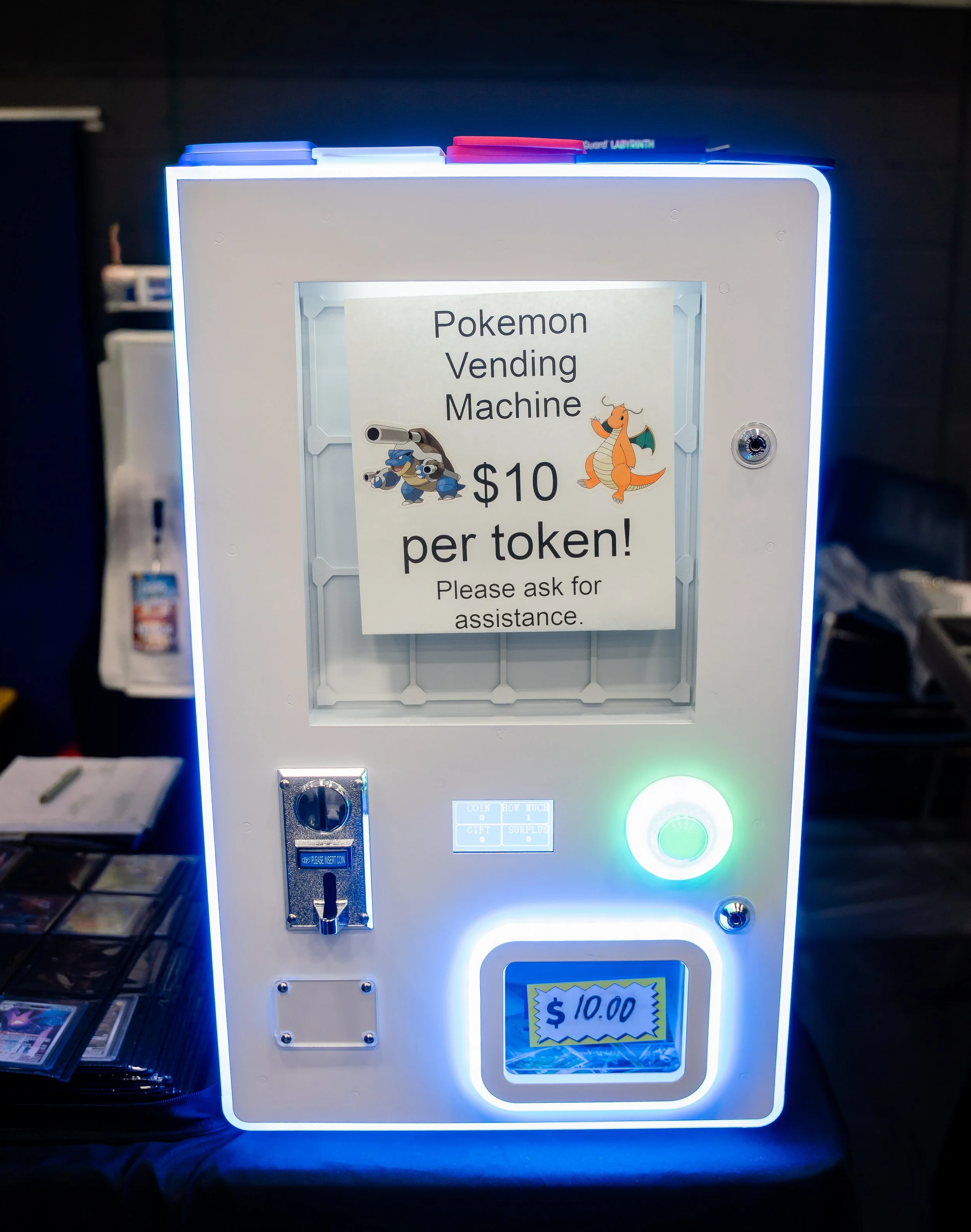 Photo of a Pokémon vending machine with a sign advertising Pokémon tokens for $10 each. The machine features Pokémon characters and a digital display showing a price of $10.00.