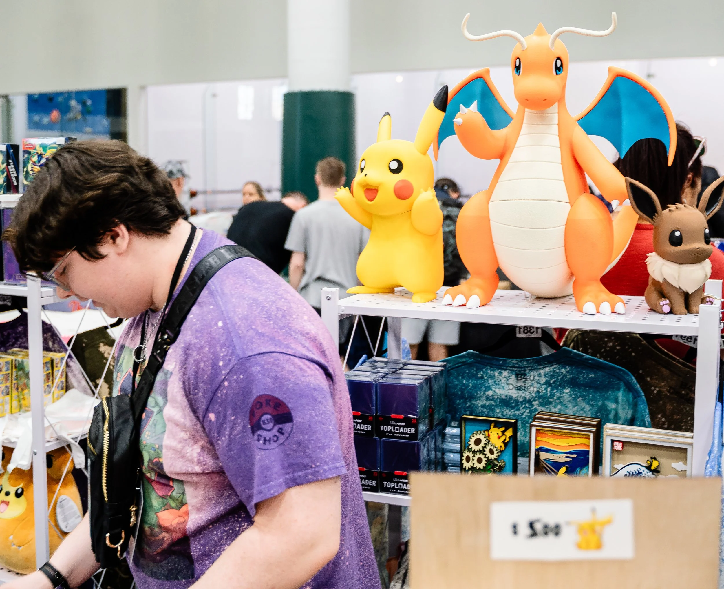 Display of Pokémon plush toys including Pikachu, Dragonite, Eevee, and other Pokémon characters at a convention or store.