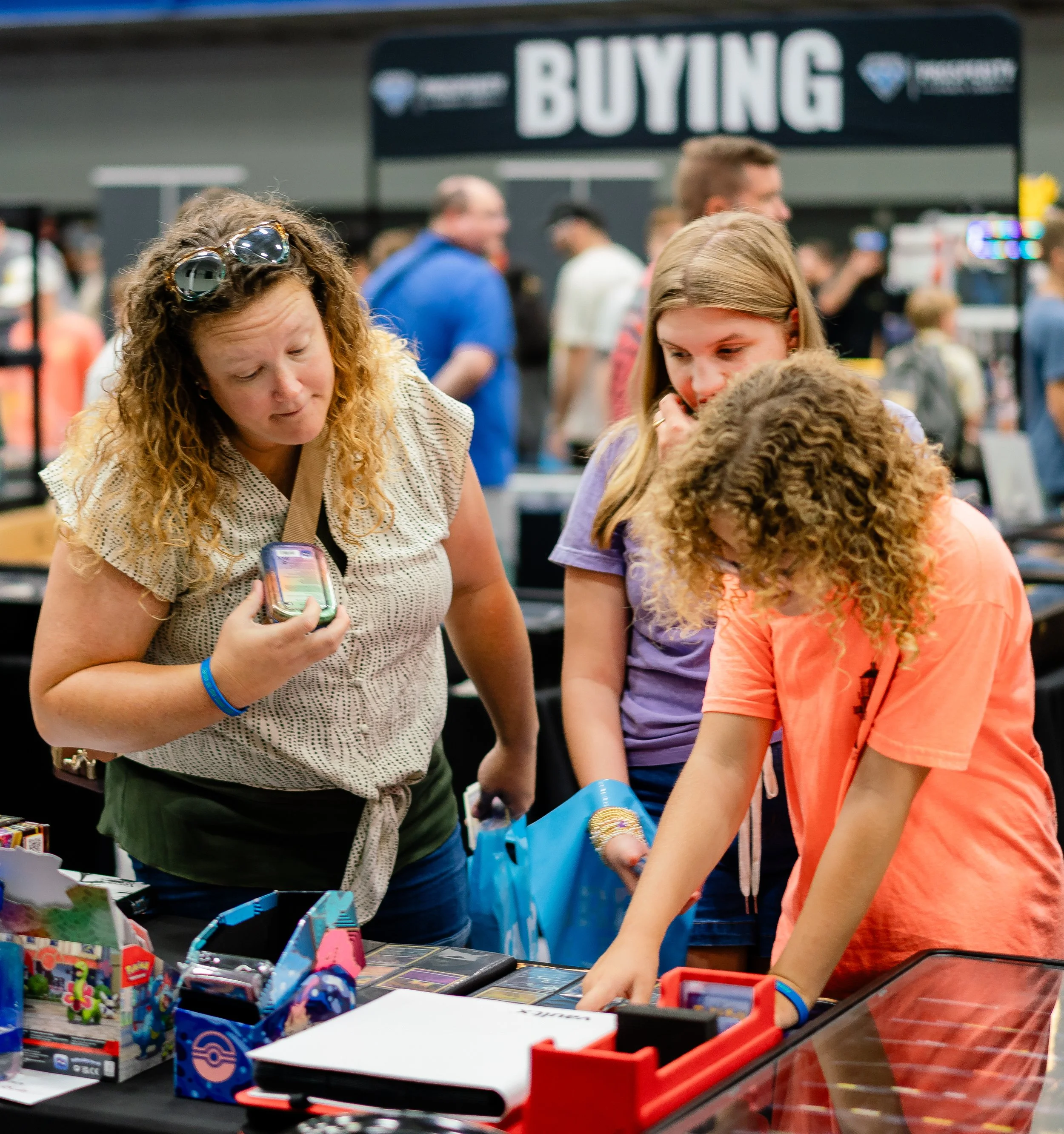 People browsing toys and collectibles at a store with a sign that reads 'BUYING' in the background.