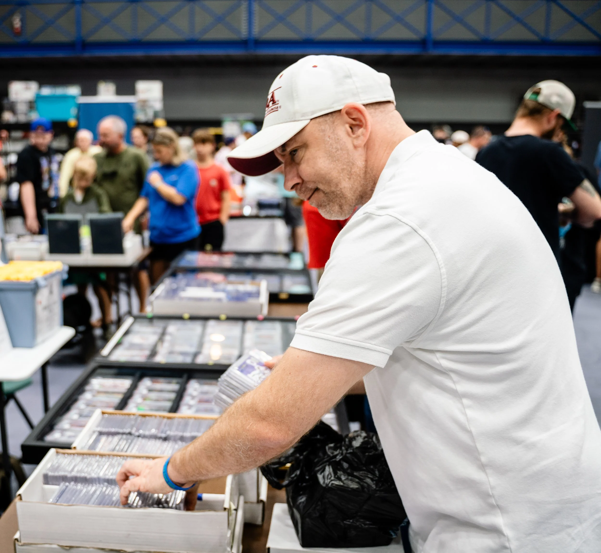 Person leaning over a display of vinyl records at a record store with other shoppers in the background.