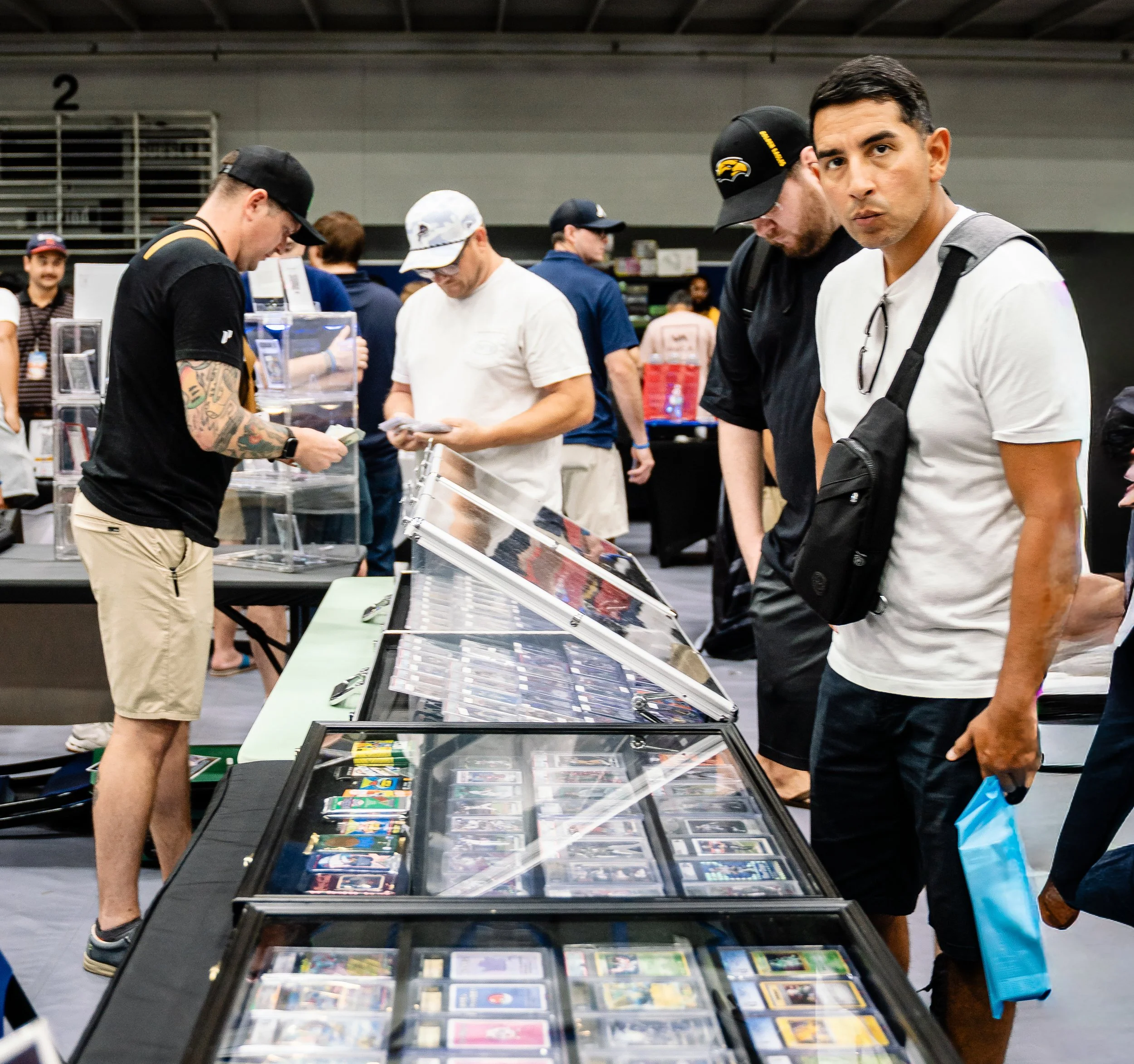People browsing and buying cards and collectibles at a convention or trade show.