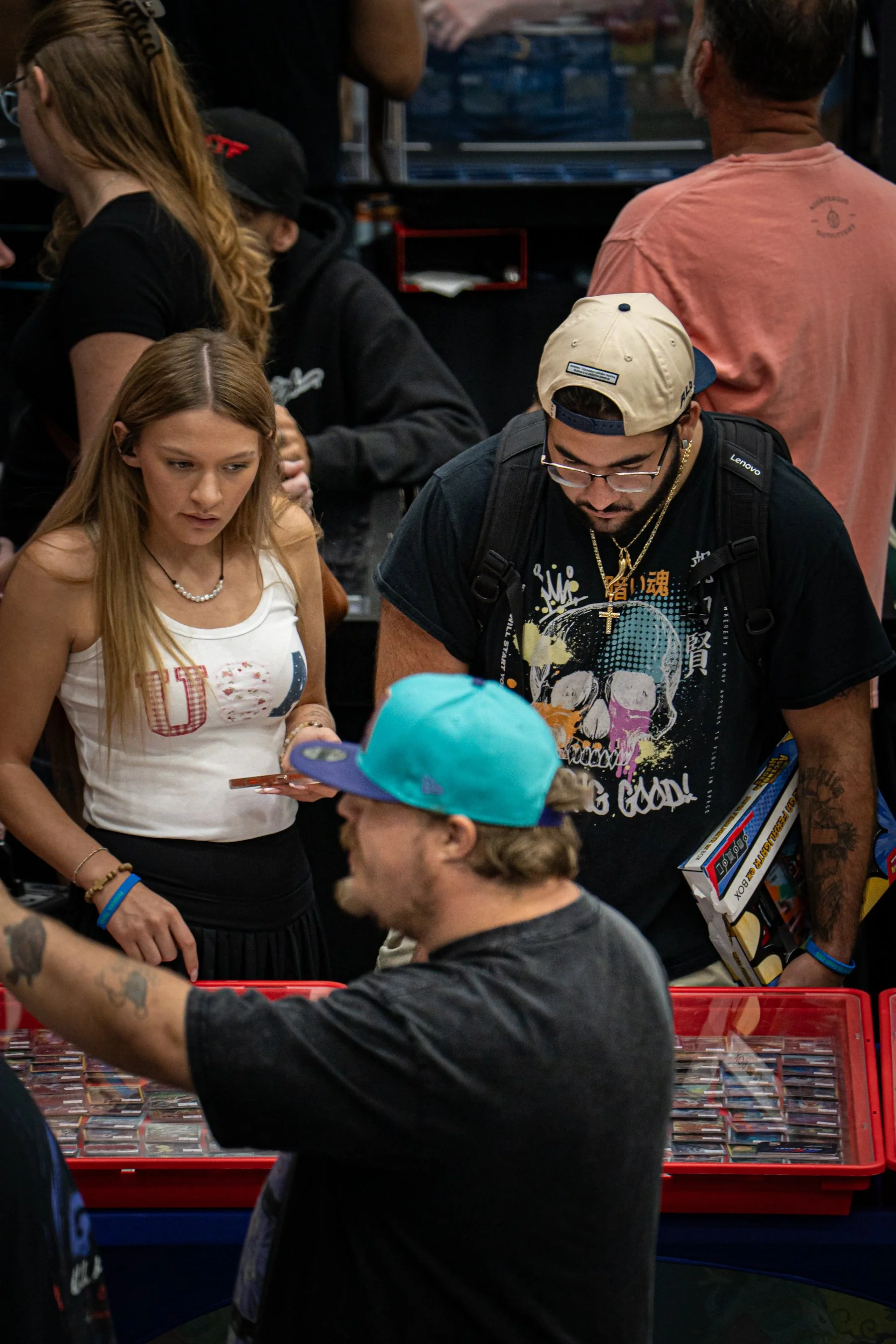 People shopping at a store with a table full of trading cards and boxes of toys.