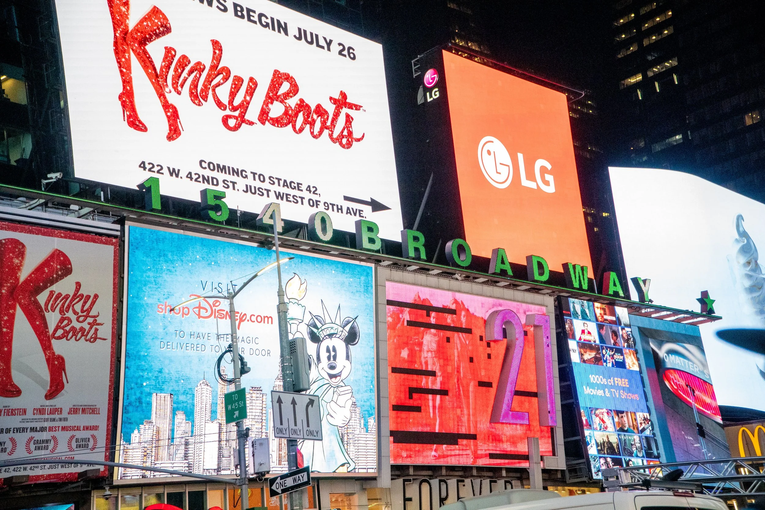 Two men stand in front of a Nasdaq building with a large Nowports advertisement on the digital screen above them.