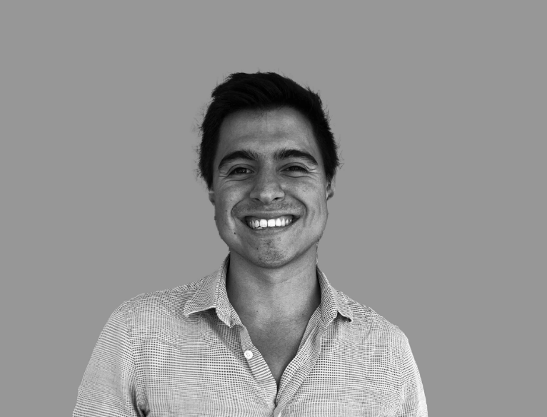 Black and white portrait of a man smiling in a collared shirt against a plain background.