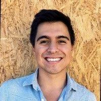 Black and white portrait of a man smiling in a collared shirt against a plain background.