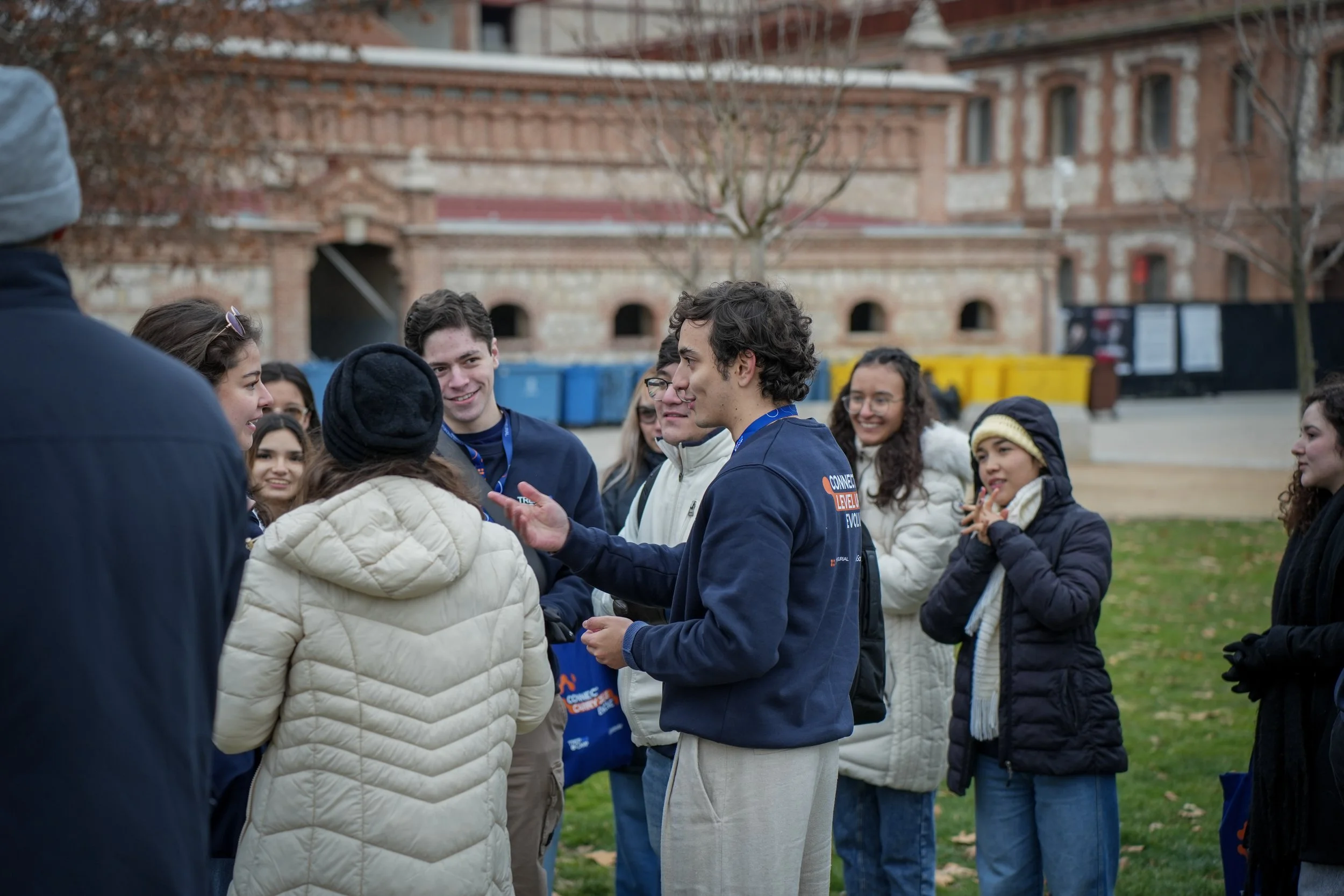 Person with short blonde hair and wearing a black blazer against a blue background.