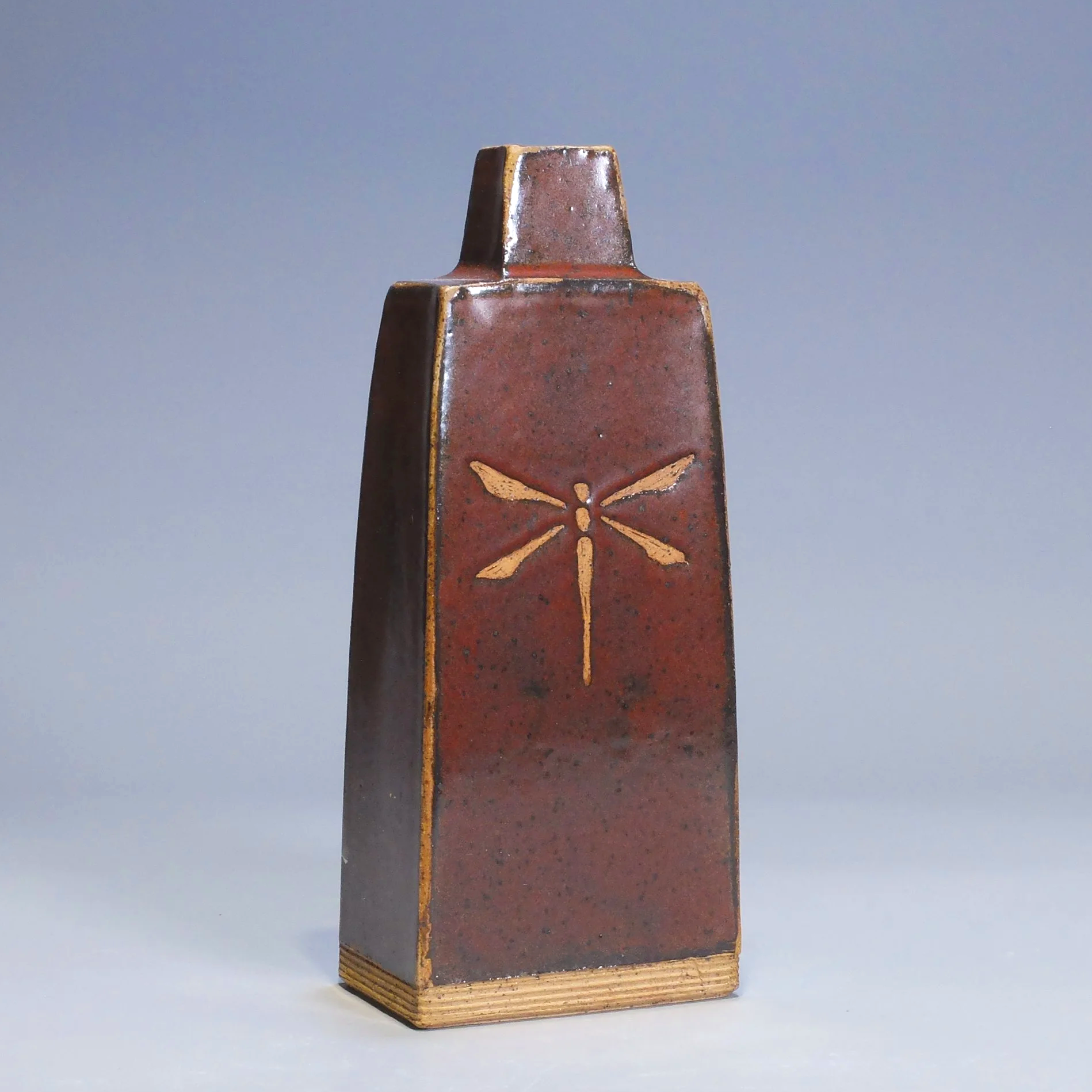 Bottle/Decanter, 2026. Speckled stoneware, red iron oxide glaze, dragonfly motif. 8.5"T, 3.5"W, 2.25"D