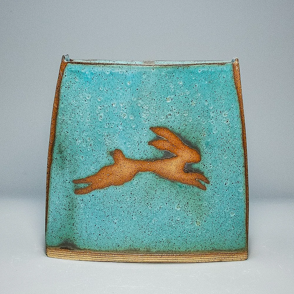 Pocket Vase, 2026. Speckled stoneware, turquoise matte glaze, leaping hare motif. 9"W, 9.5"H, 3.25"D