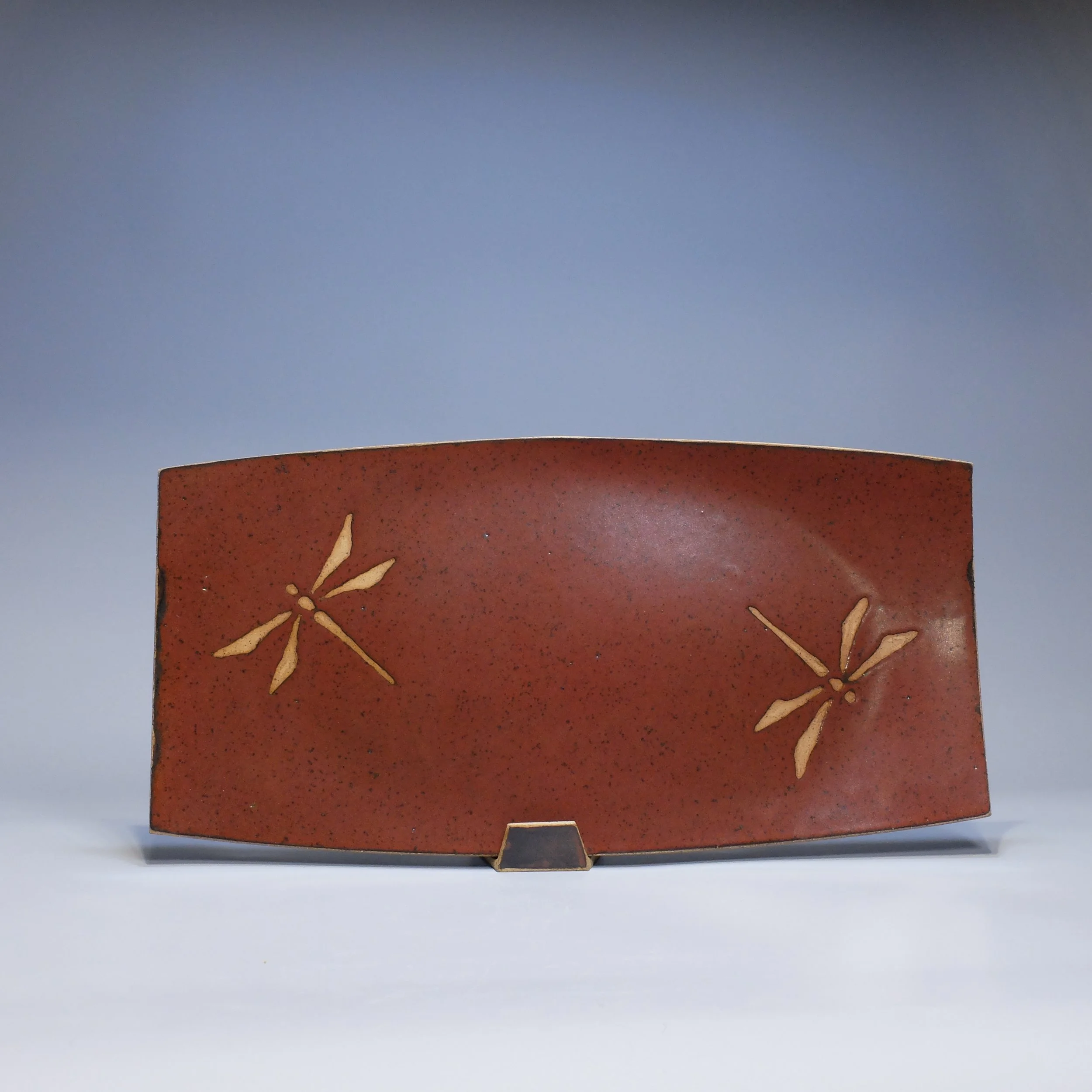 SOLD Platter, 2026. Speckled stoneware, red iron oxide glaze, dragonfly motif. 17.25"L, 8.75"W, 0.75"D.