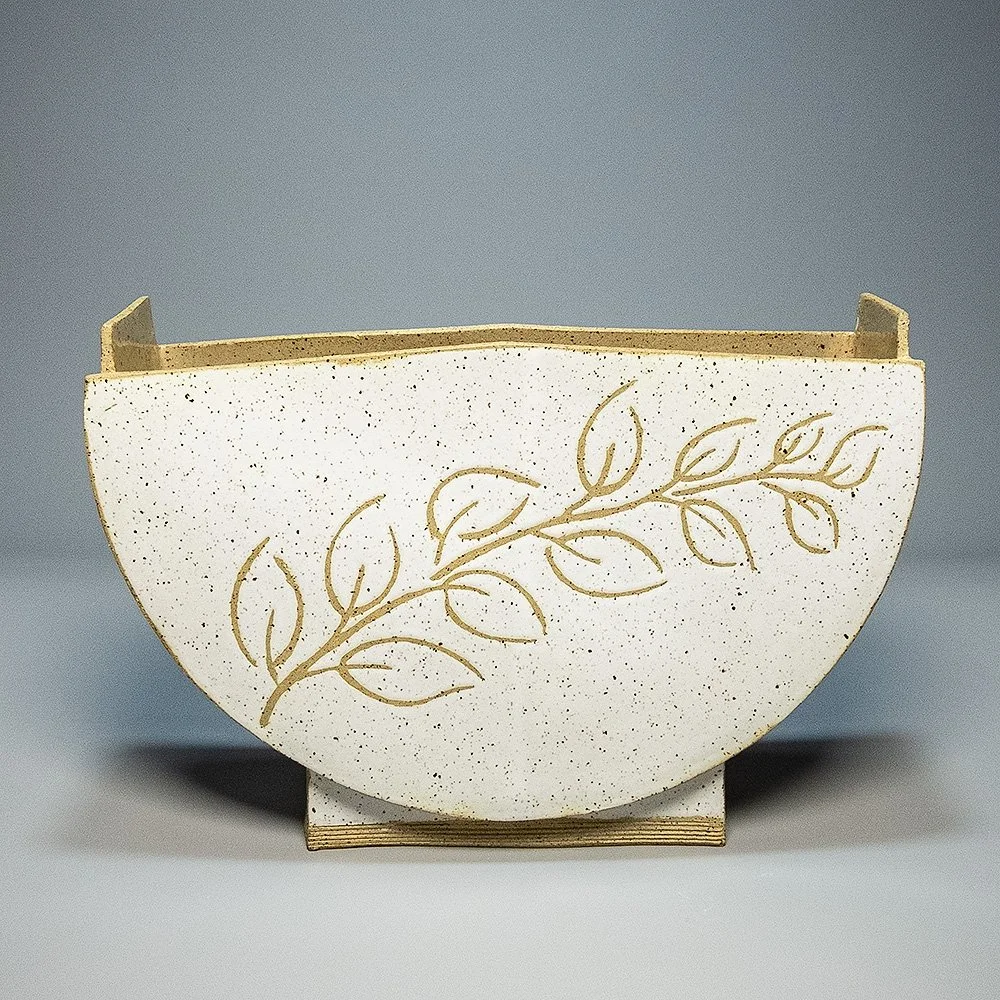 Half-Moon Vase, 2026. Speckled stoneware, white glaze, leaf & branch motif. 12.25"W, 8.25"T, 3.75"D