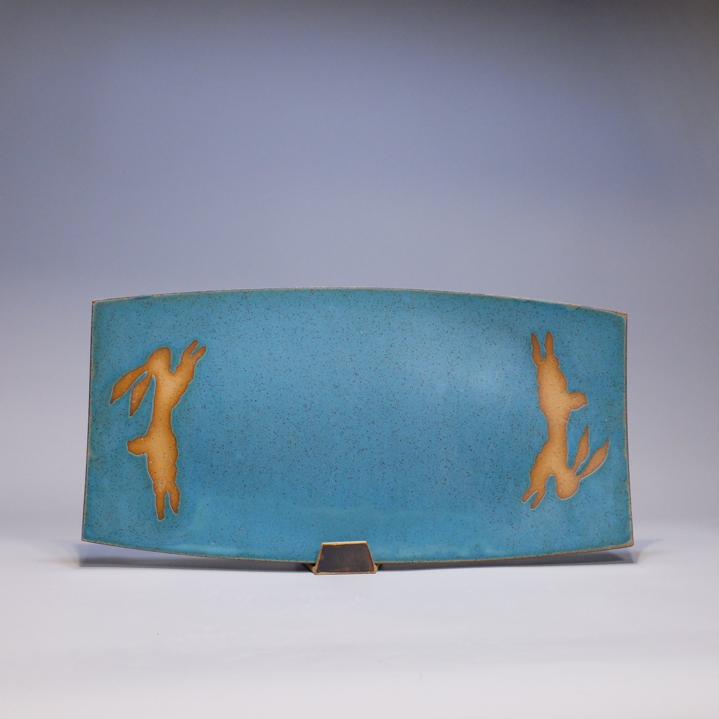 Platter, 2026. Speckled stoneware, turquoise glaze, leaping hare motif. 17.25"L, 8.75"W, 0.75"D.