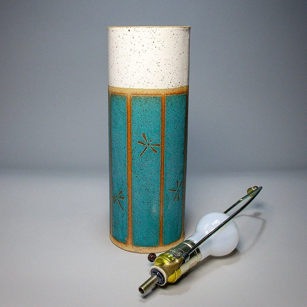 Cylinder Lamp Base 2026. Speckled stoneware, white and turquoise matte glaze, dragonfly motif. 12"H, 4.5"Dia.