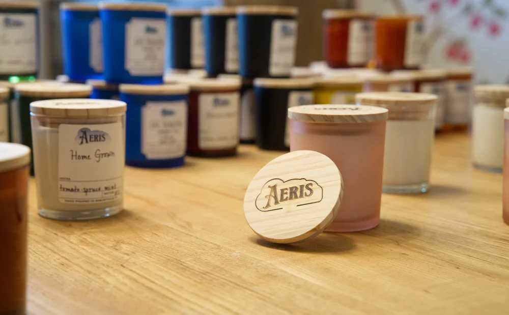 Aeris candles with hand-branded wooden lids on a worktable
