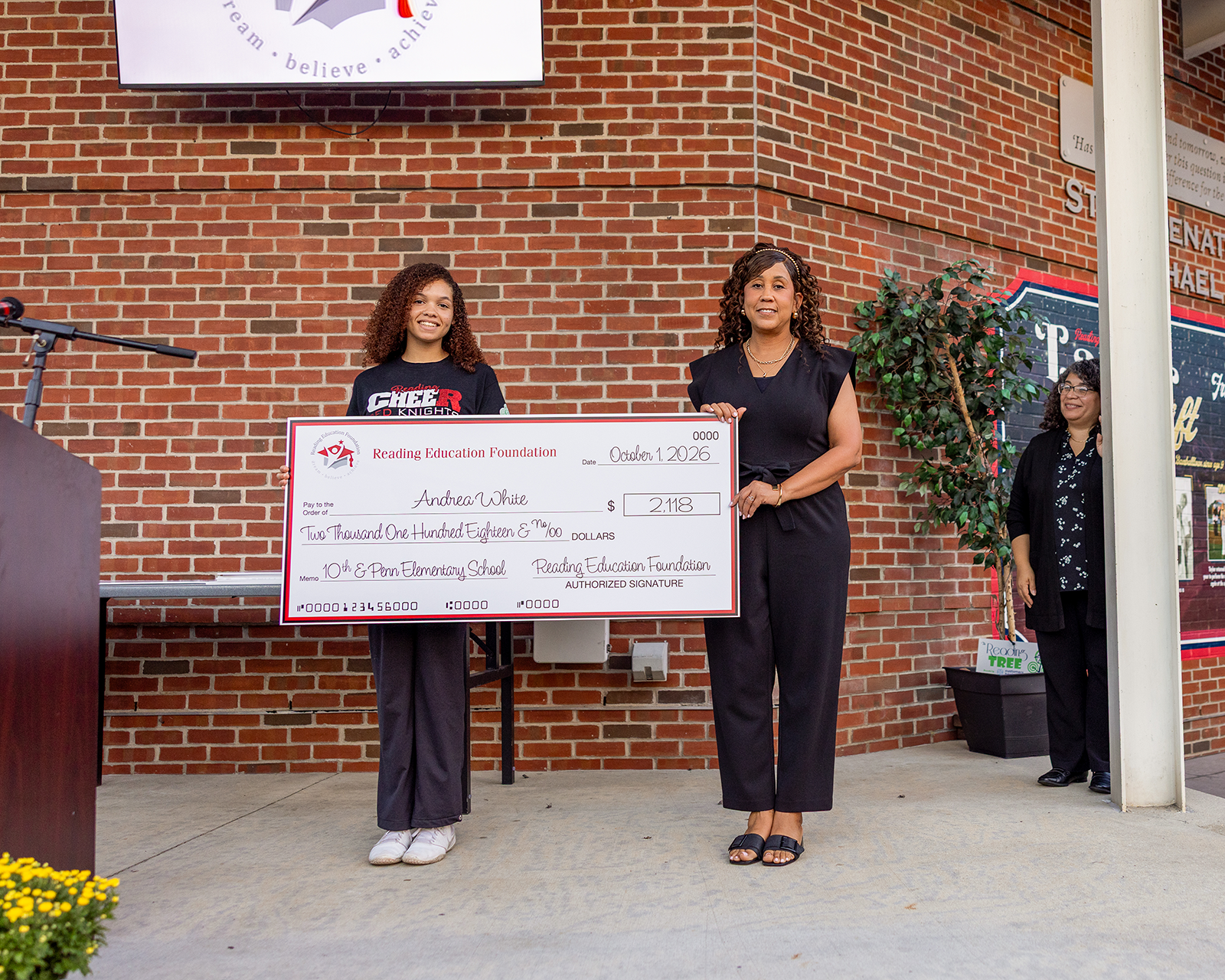 Photo of Andrea White holding a large check from the Reading Education Foundation for her grant