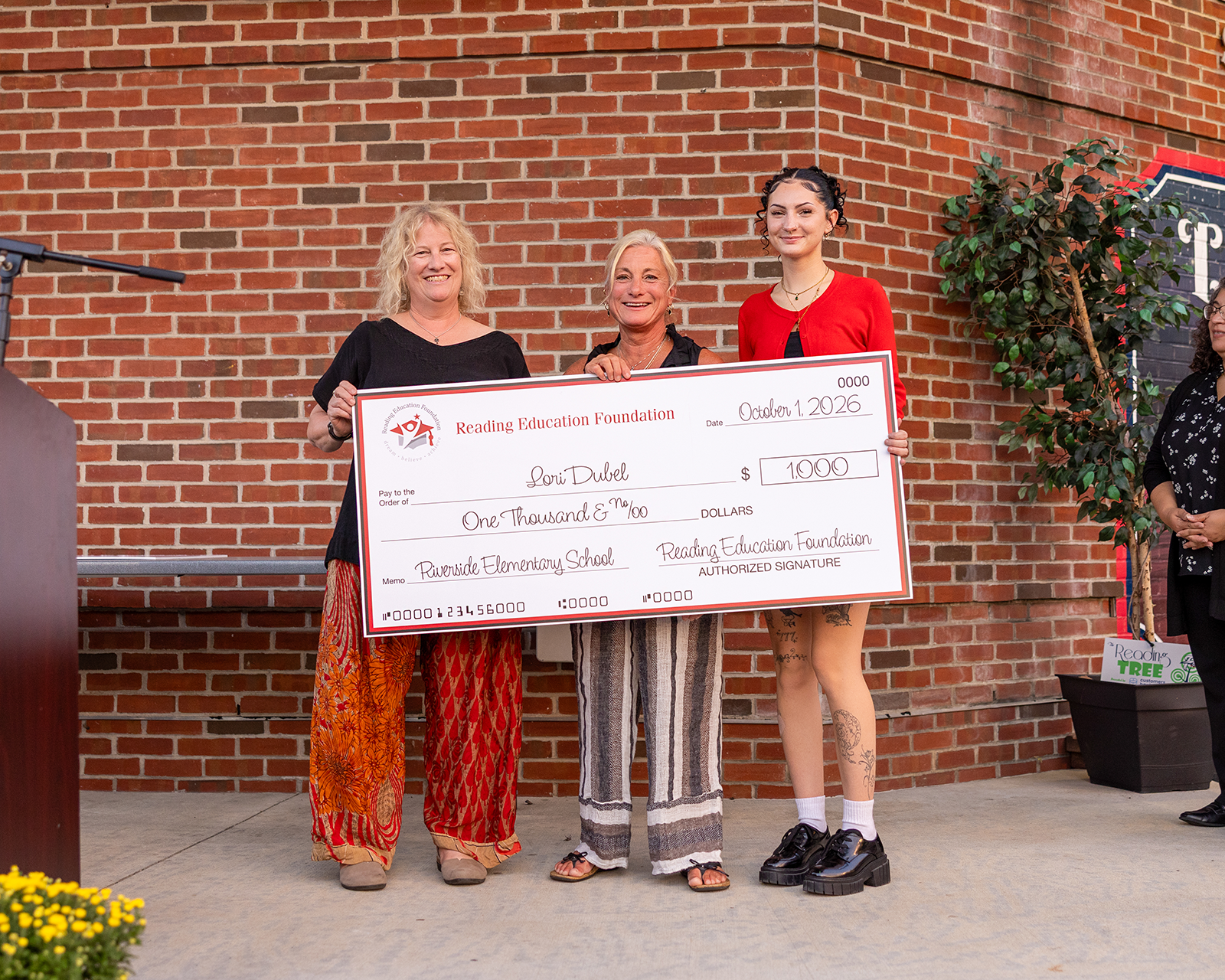 Lori Dubel holding a large check from Reading Education Foundation for her teacher grant.