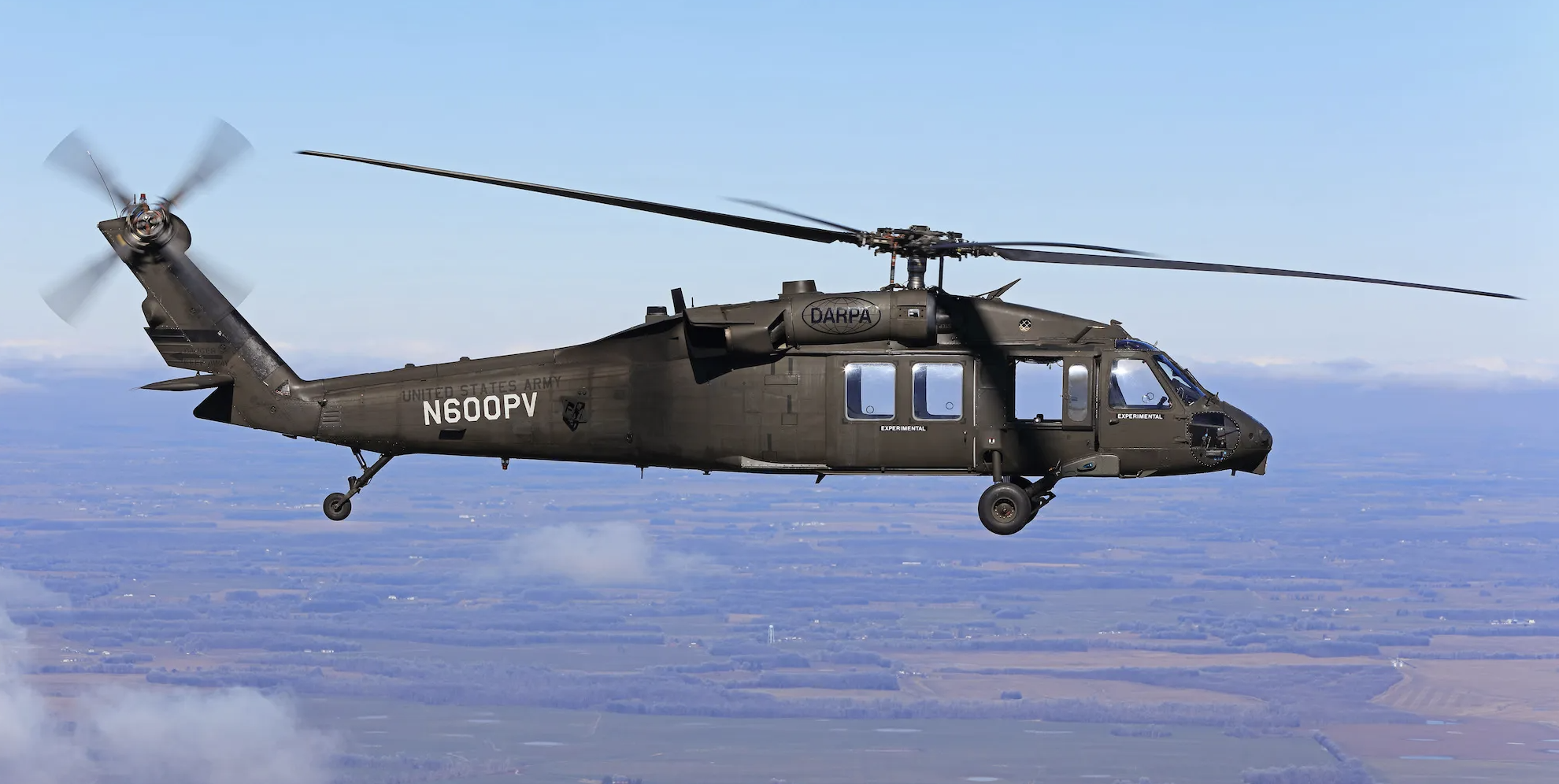 Image of black hawk helicopter flying over countryside.